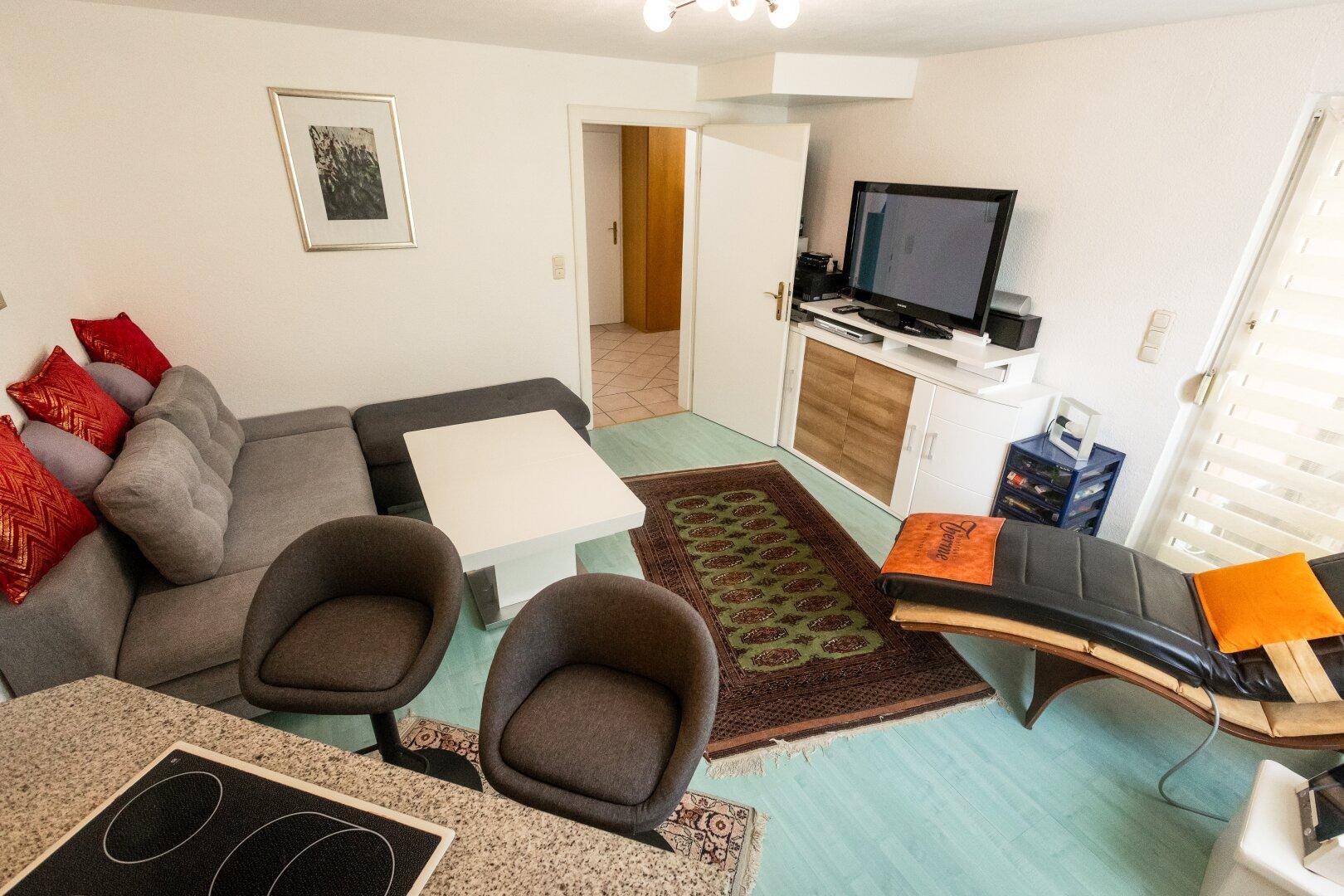 Gemütlicher Wohnbereich mit Sofa, Fernseher und Zugang zu einem weiteren Raum.