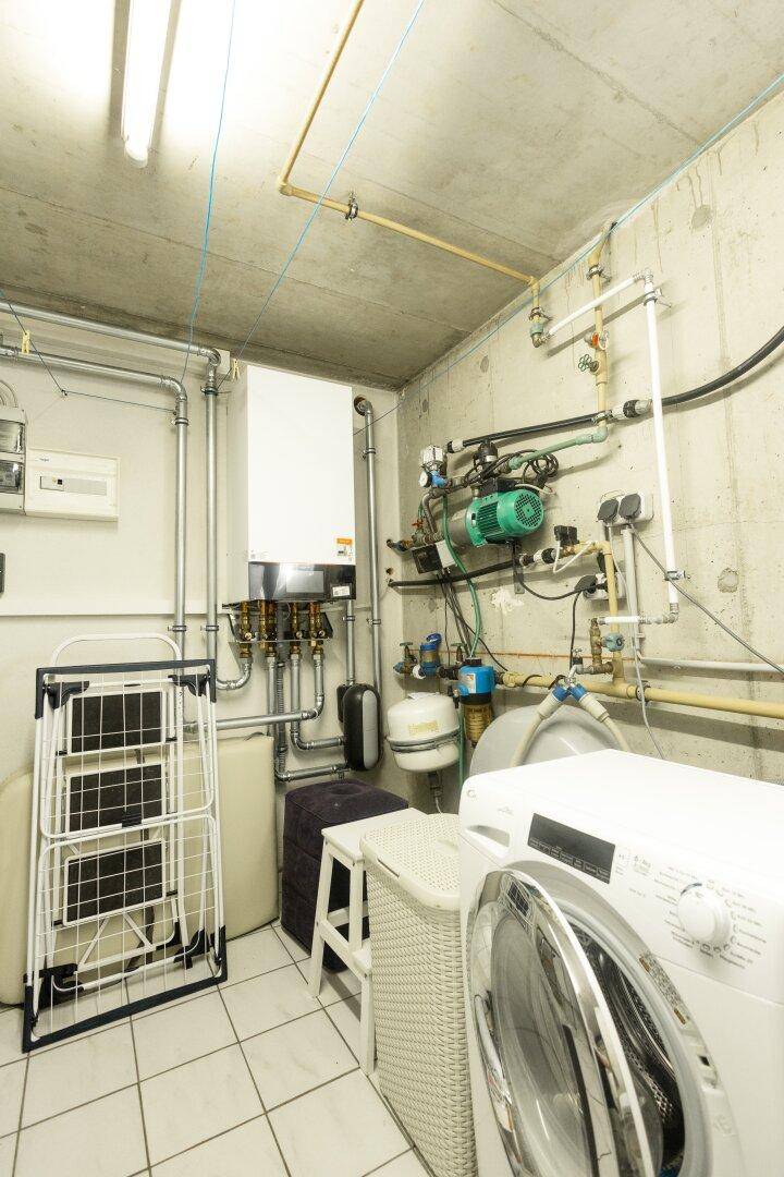 Technikraum mit Heizungsanlage, Waschmaschine und Wäscheständer.