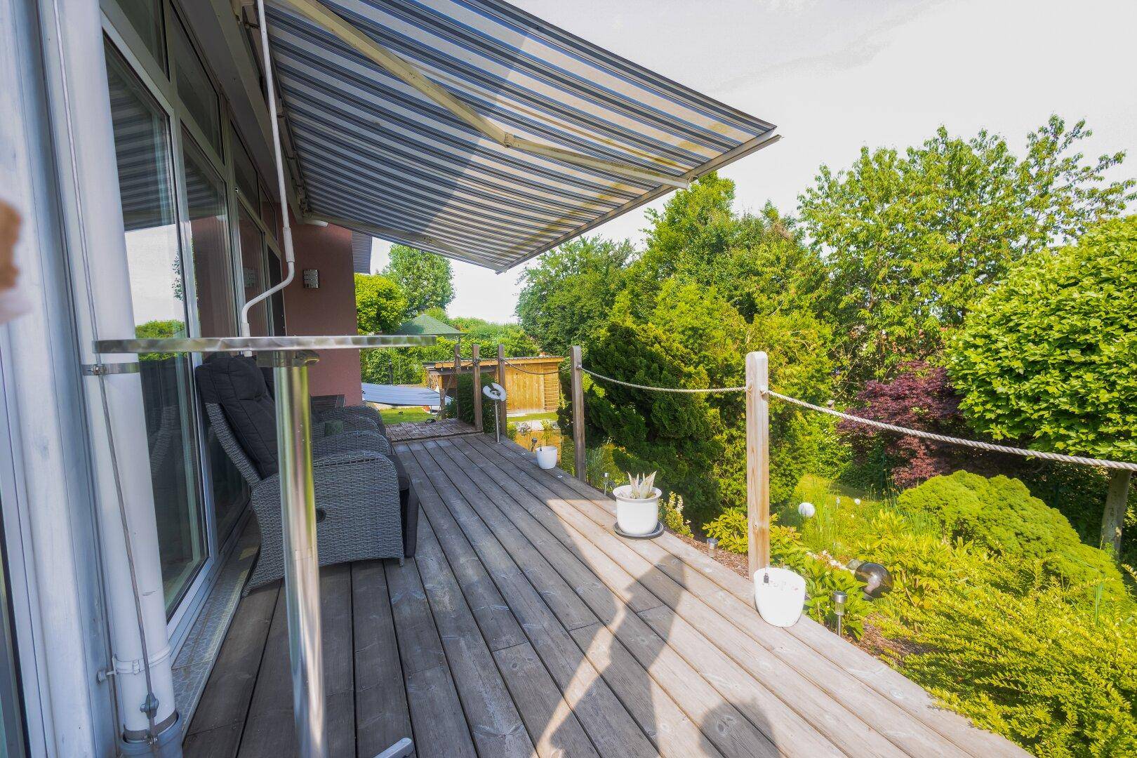 Geräumige Holzterrasse mit Outdoor-Sitzgelegenheiten und Blick ins Grüne.