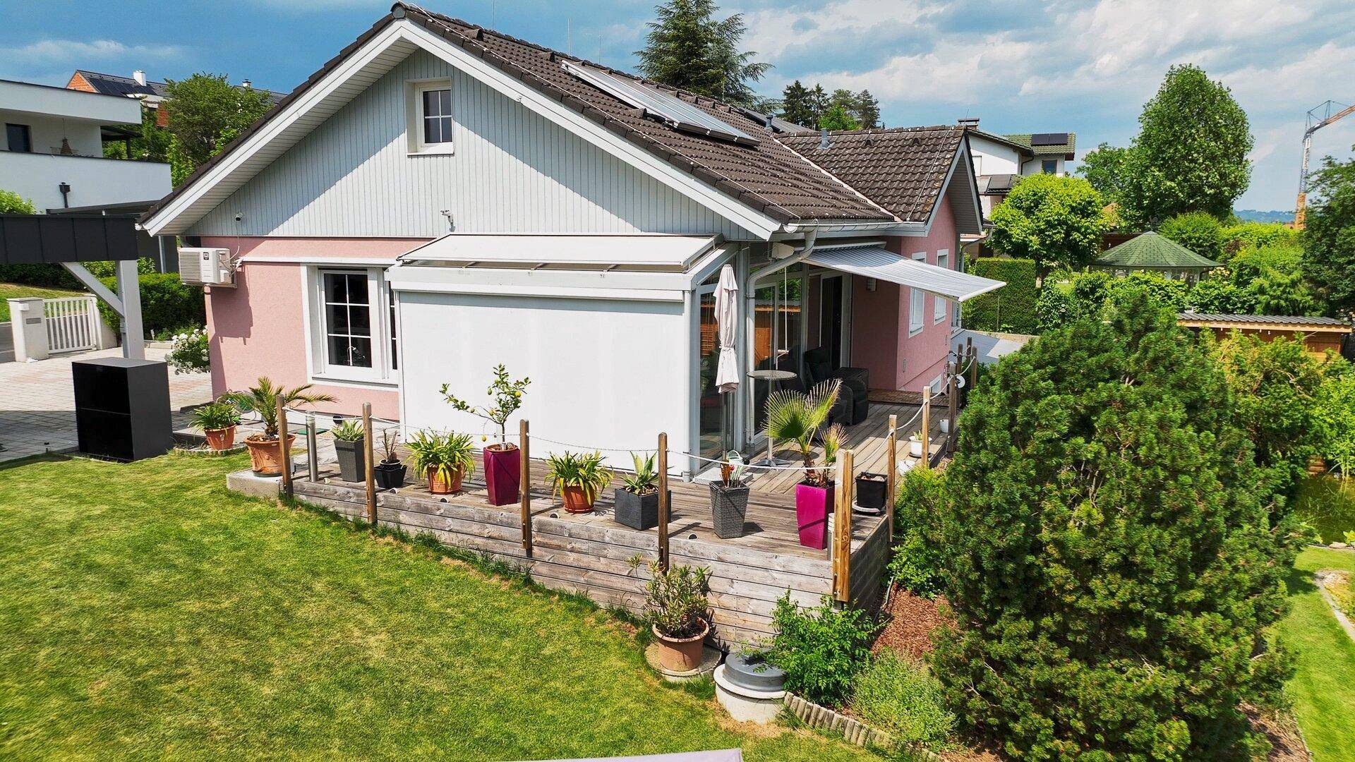 Vogelperspektive des Hauses mit großer Holzterrasse und gepflegtem Garten.