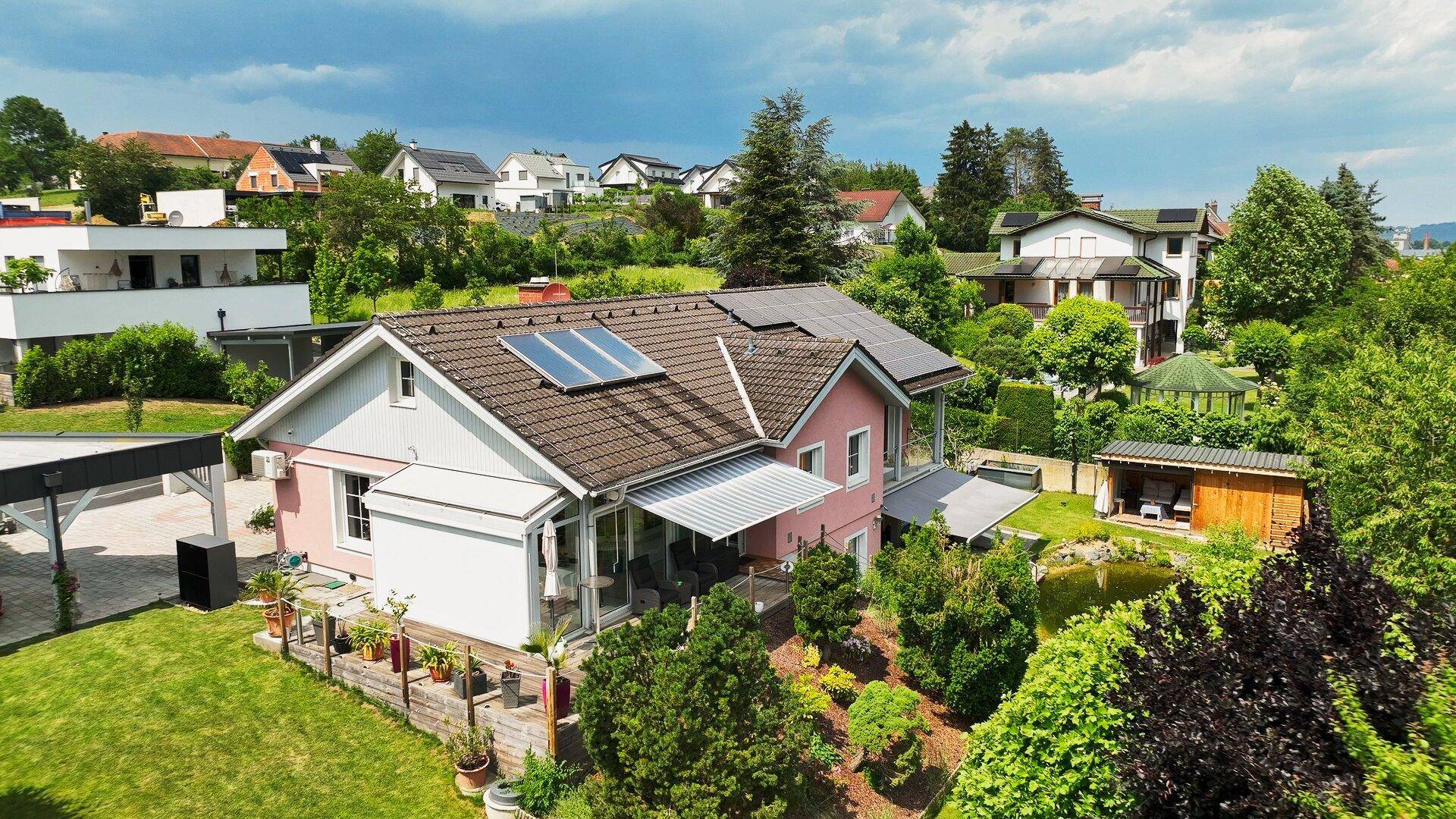 Weitläufige Ansicht des Hauses mit Solaranlagen auf dem Dach und umliegender Natur.