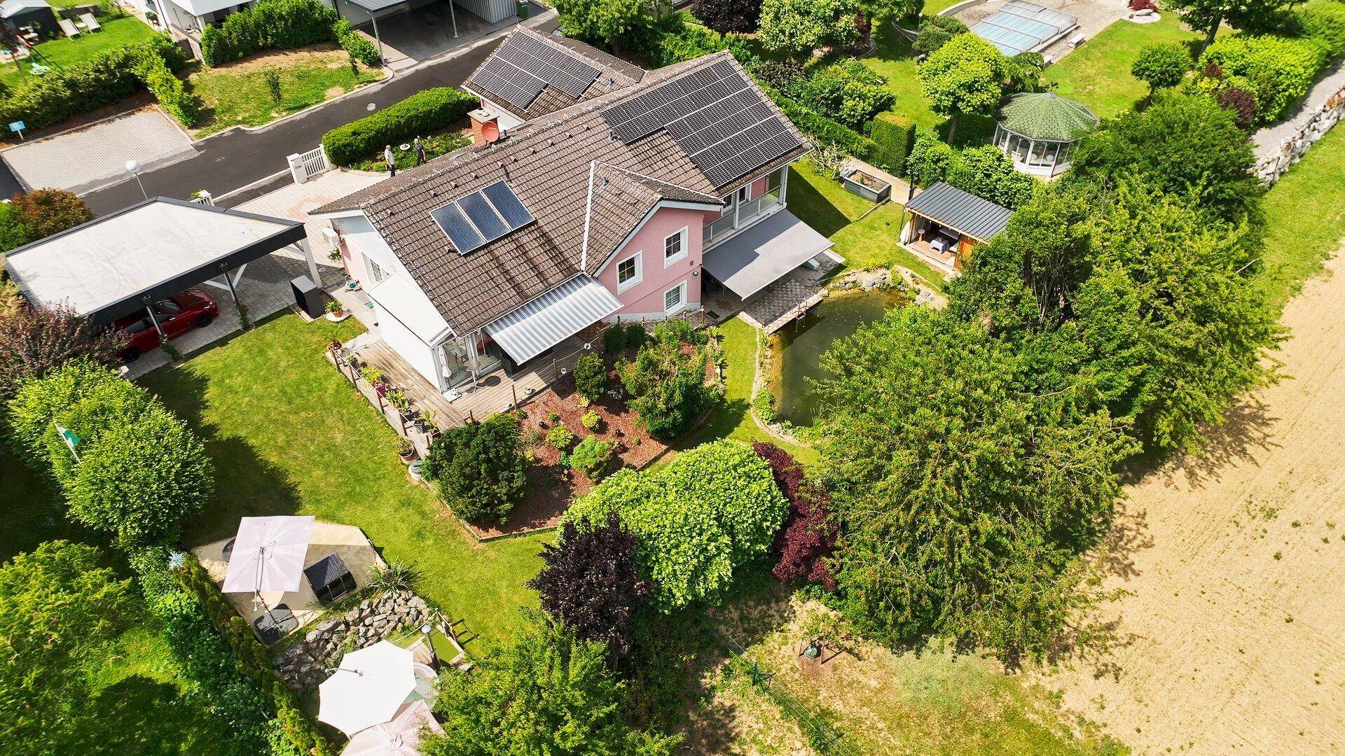 Luftaufnahme des Anwesens mit großem Garten, Teich und Carport.