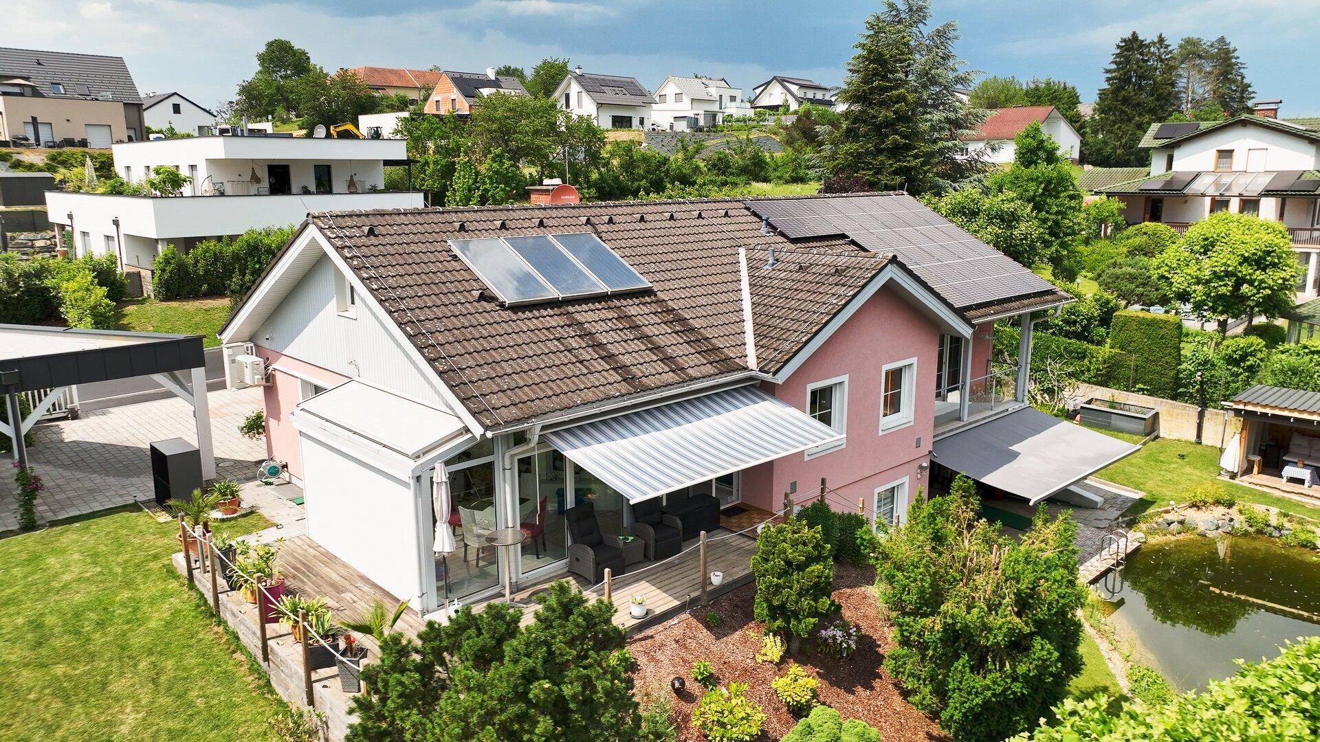 Haus mit Solaranlagen, großer Terrasse und weitläufigem Gartenbereich.