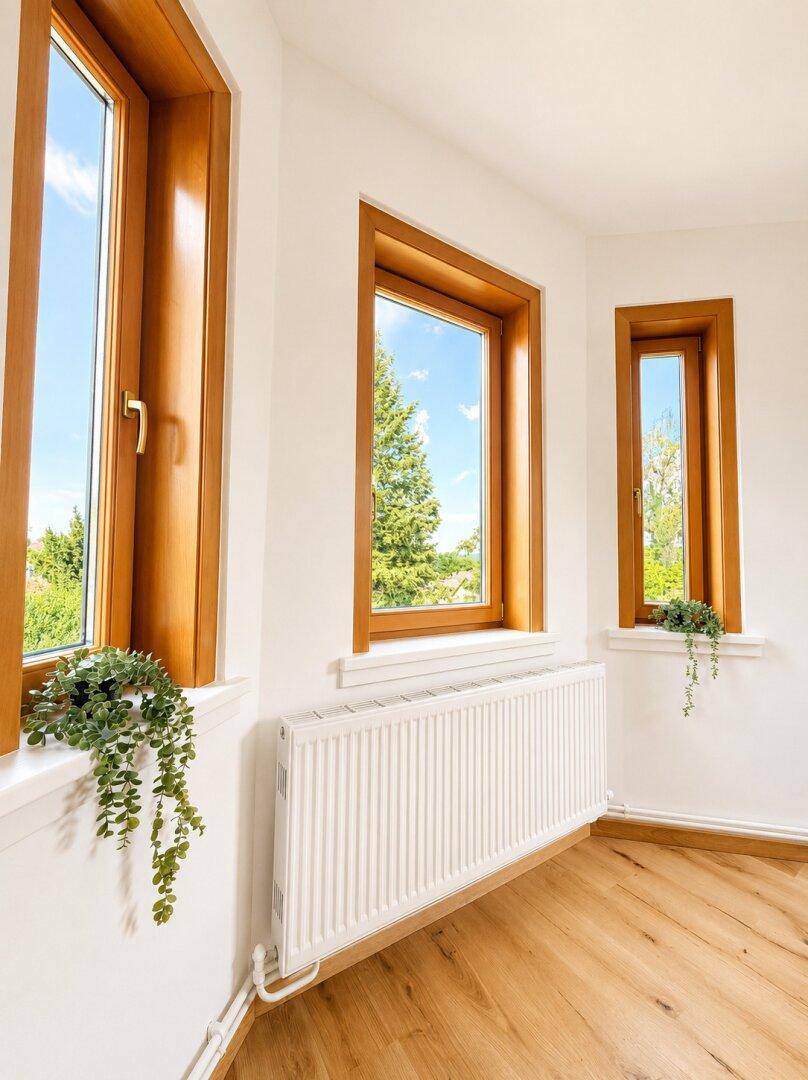 Detailansicht der Holzfenster im Wohnzimmer mit Blick auf die grüne Umgebung.