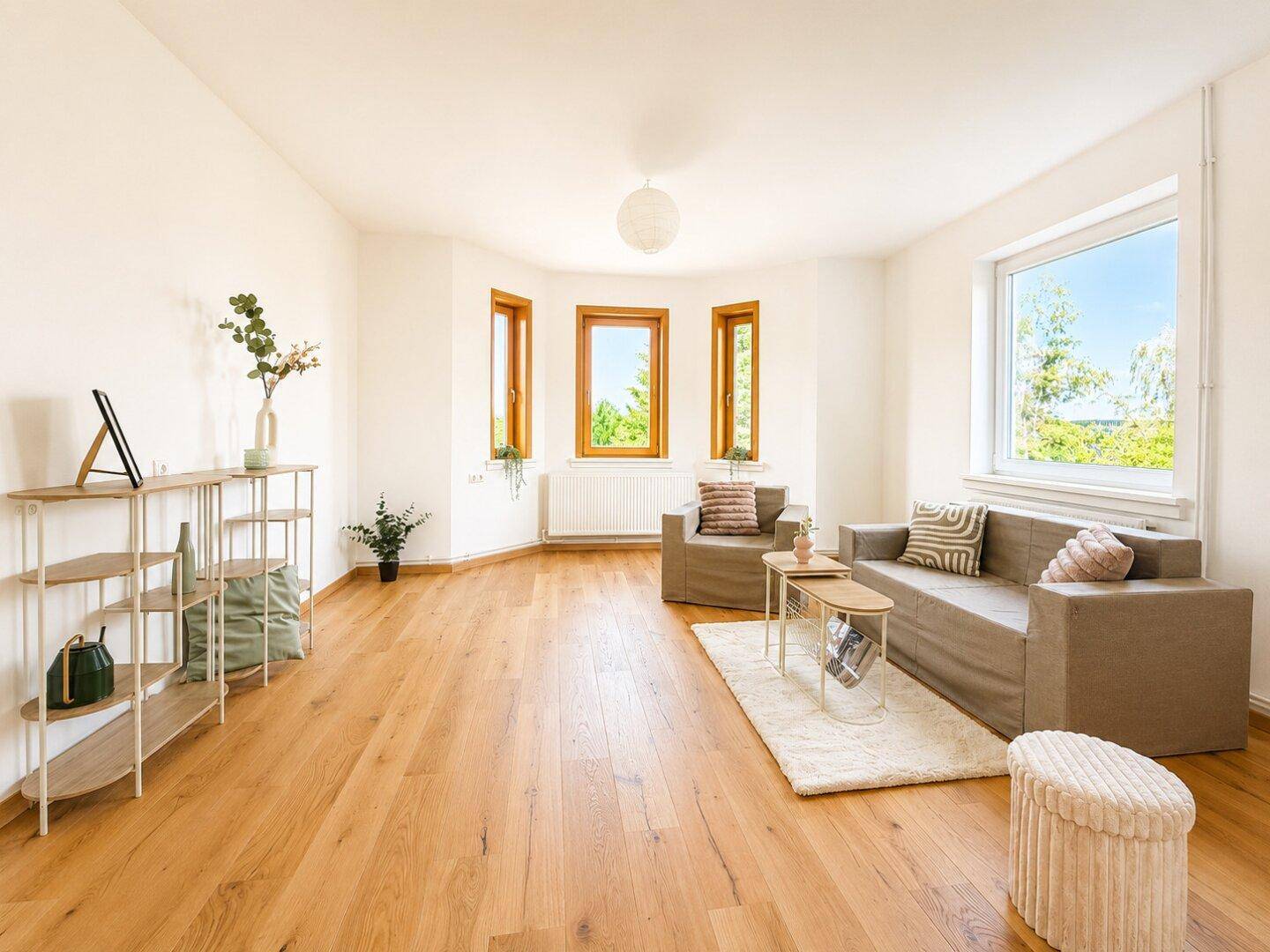 Helles Wohnzimmer mit Eichenparkett, großen Fenstern und Blick ins Grüne.