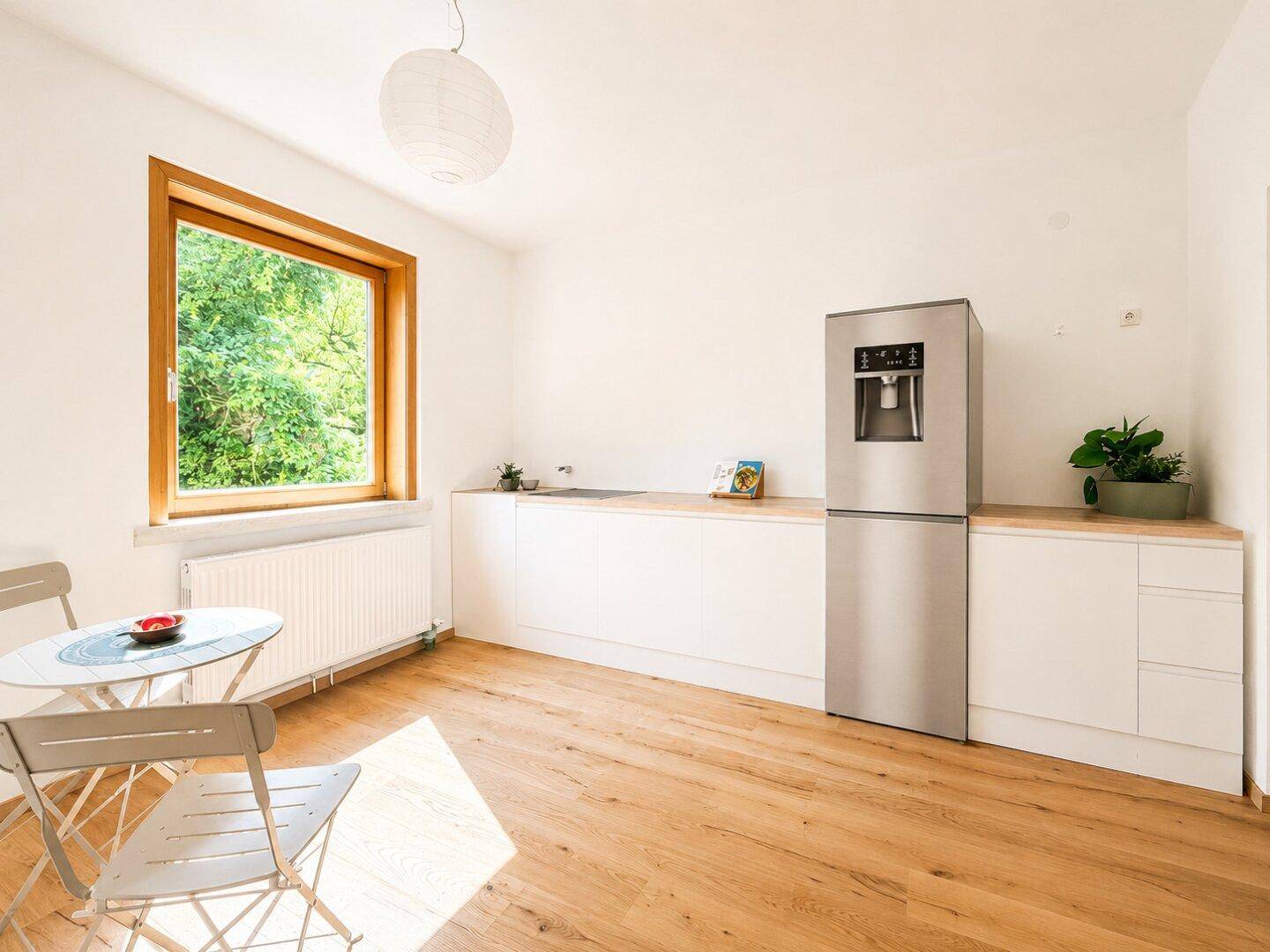 Moderne Küche mit weißen Unterschränken, Holzarbeitsplatte und großem Kühlschrank.