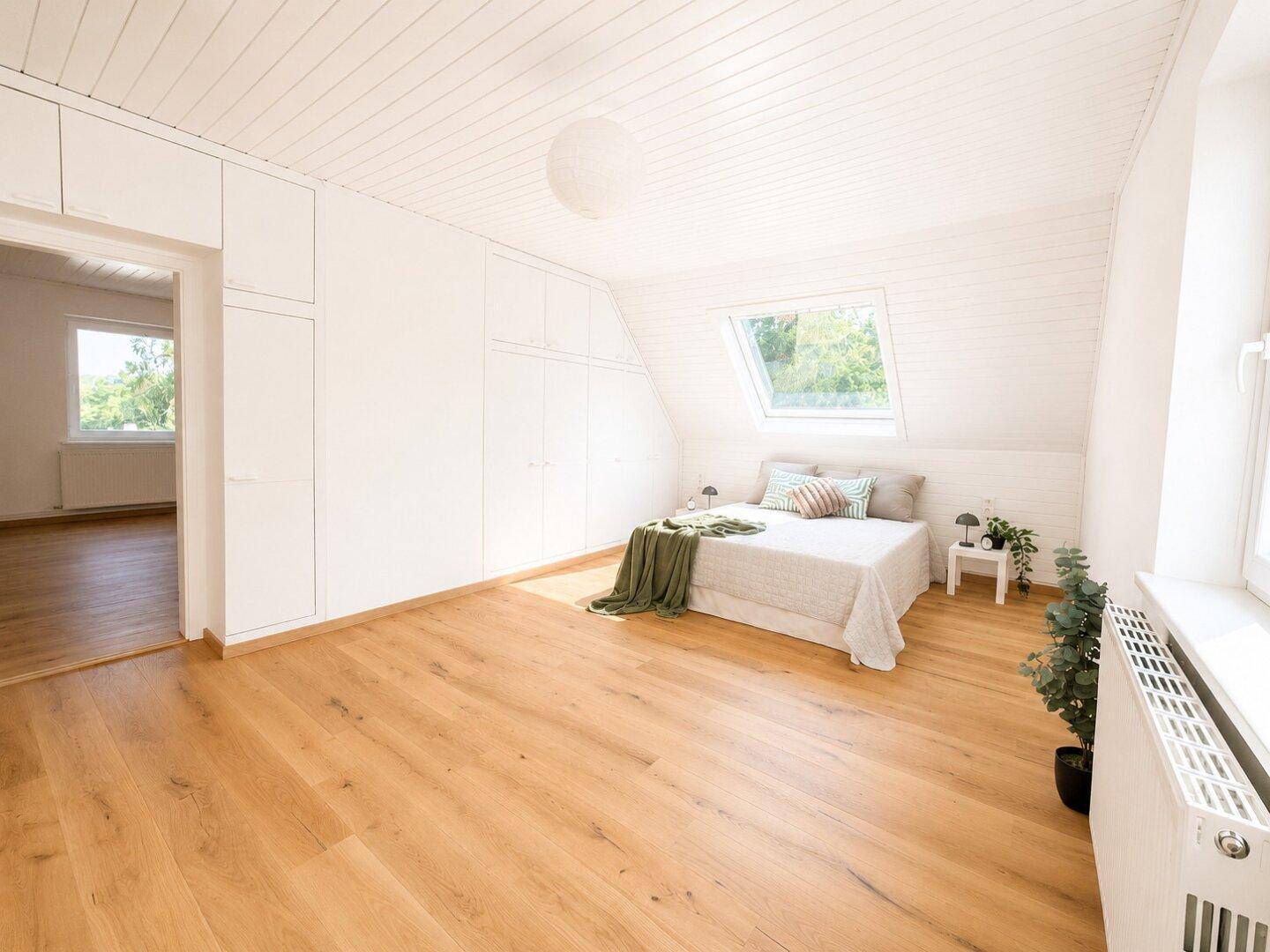 Gemütliches Schlafzimmer im Dachgeschoss mit Holzboden, Einbauschränken und Dachfenster.