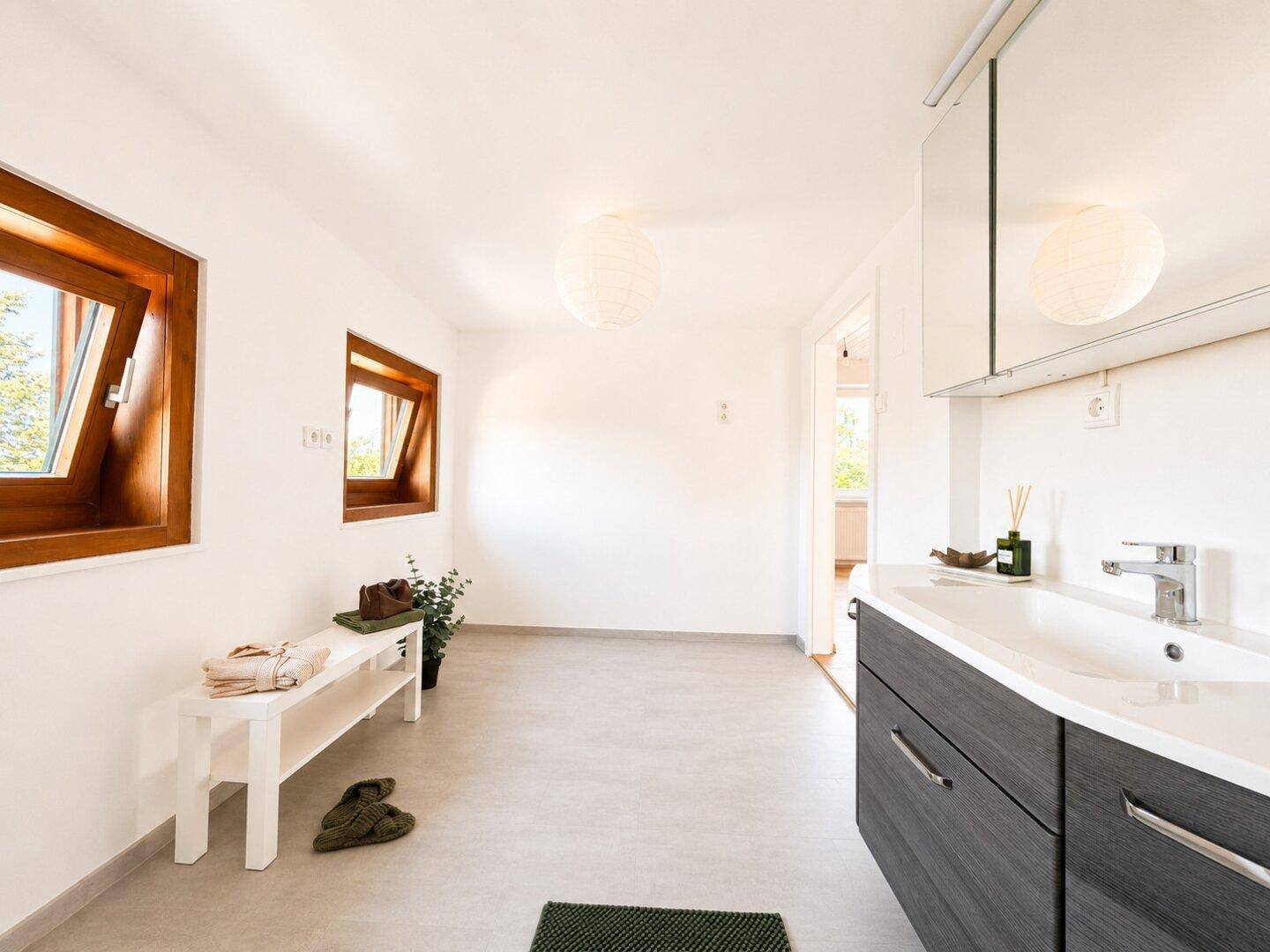 Helles Badezimmer im Dachgeschoss mit modernem Waschtisch und Spiegelschrank.