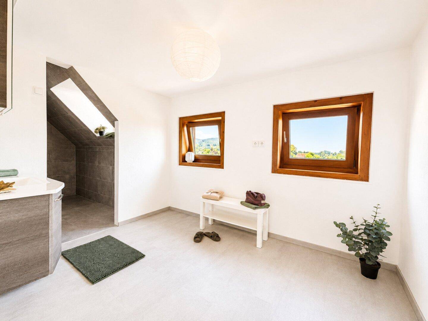 Geräumiges Badezimmer im Dachgeschoss mit Waschtisch und zwei Fenstern.