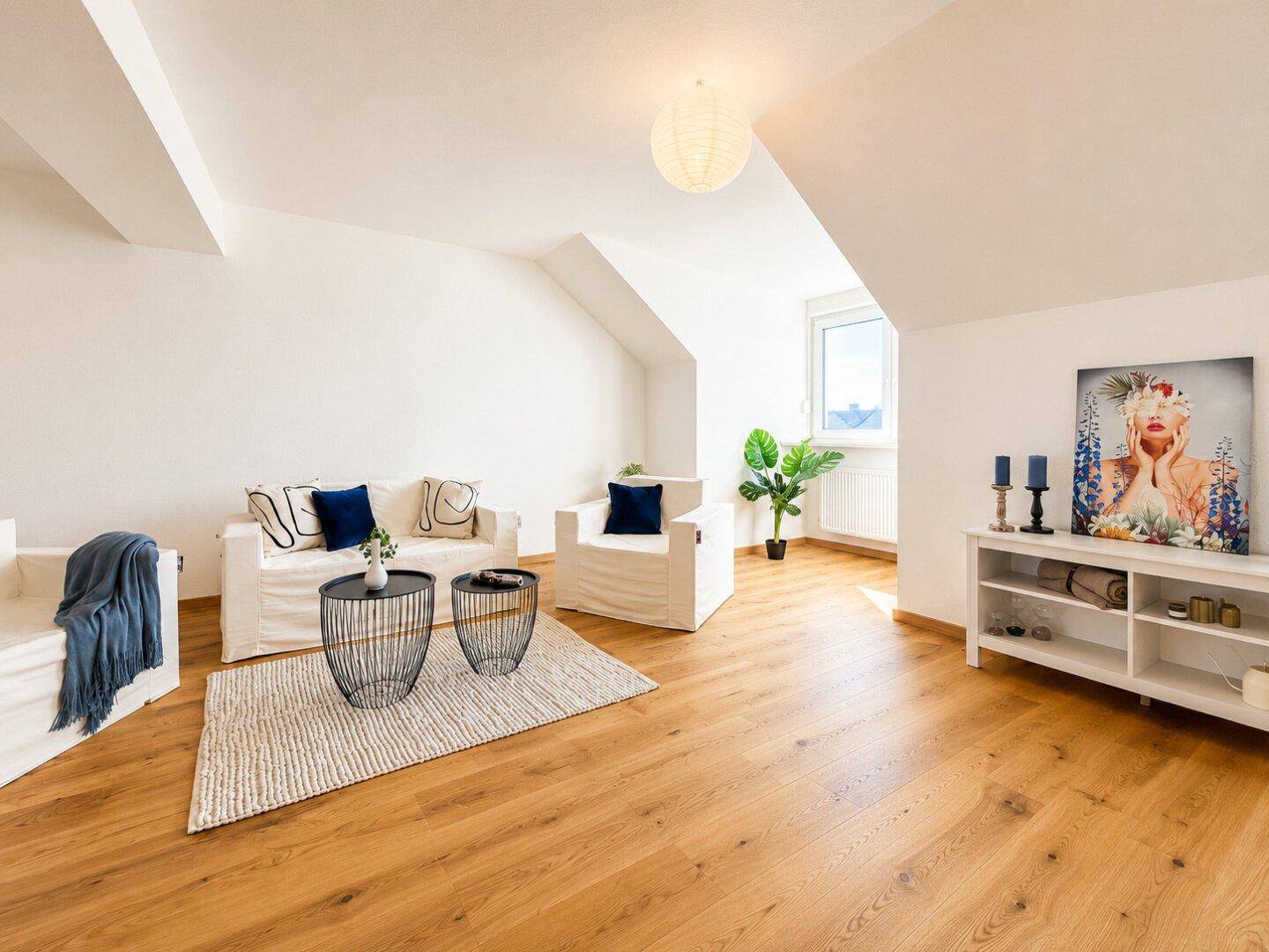 Geräumiges Wohnzimmer im Dachgeschoss mit Holzboden, bequemen Sofas und viel Tageslicht.