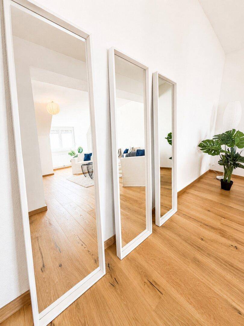 Heller Flur mit Holzboden und drei großen Spiegeln, die den Raum optisch erweitern.