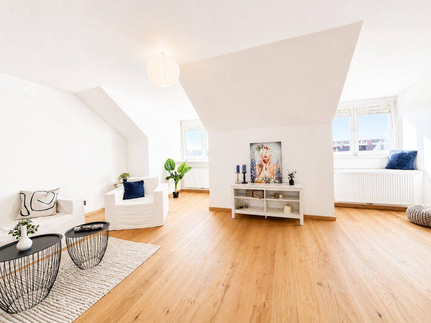 Helles Wohnzimmer mit Holzboden, weißen Sofas und einem Fenster mit Ausblick.