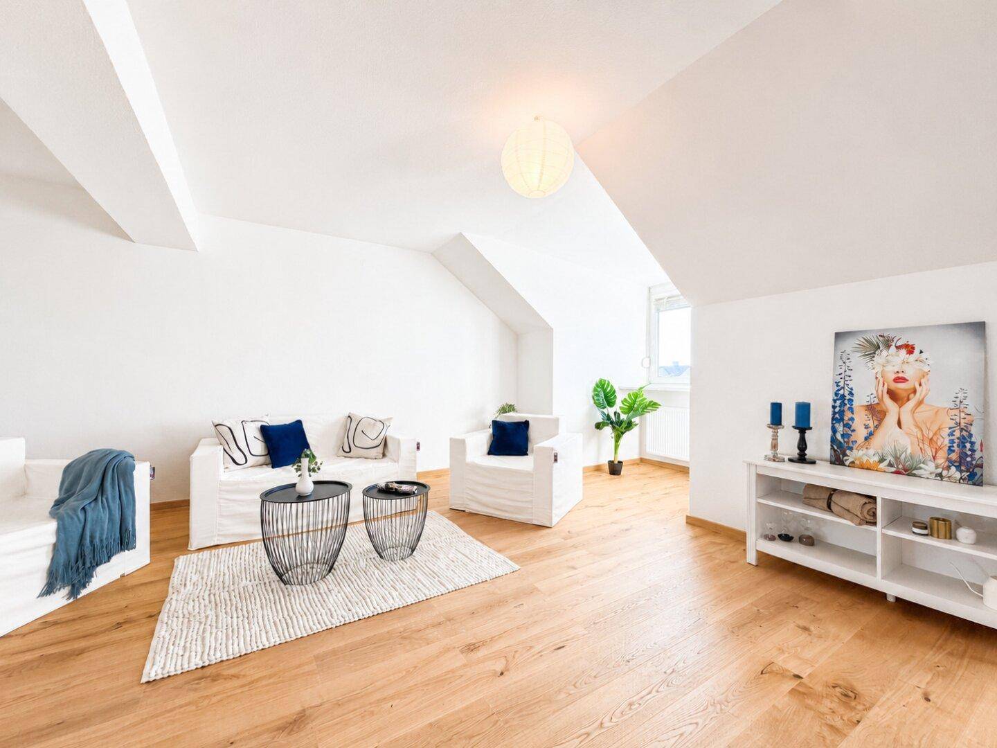 Modern eingerichtetes Wohnzimmer mit Holzboden, weißen Sofas und dekorativen Elementen.