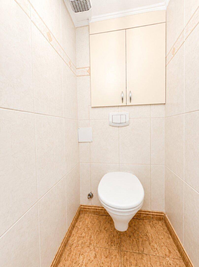 Kleines Gäste-WC mit hellen Fliesen, wandhängendem WC und praktischem Wandschrank.