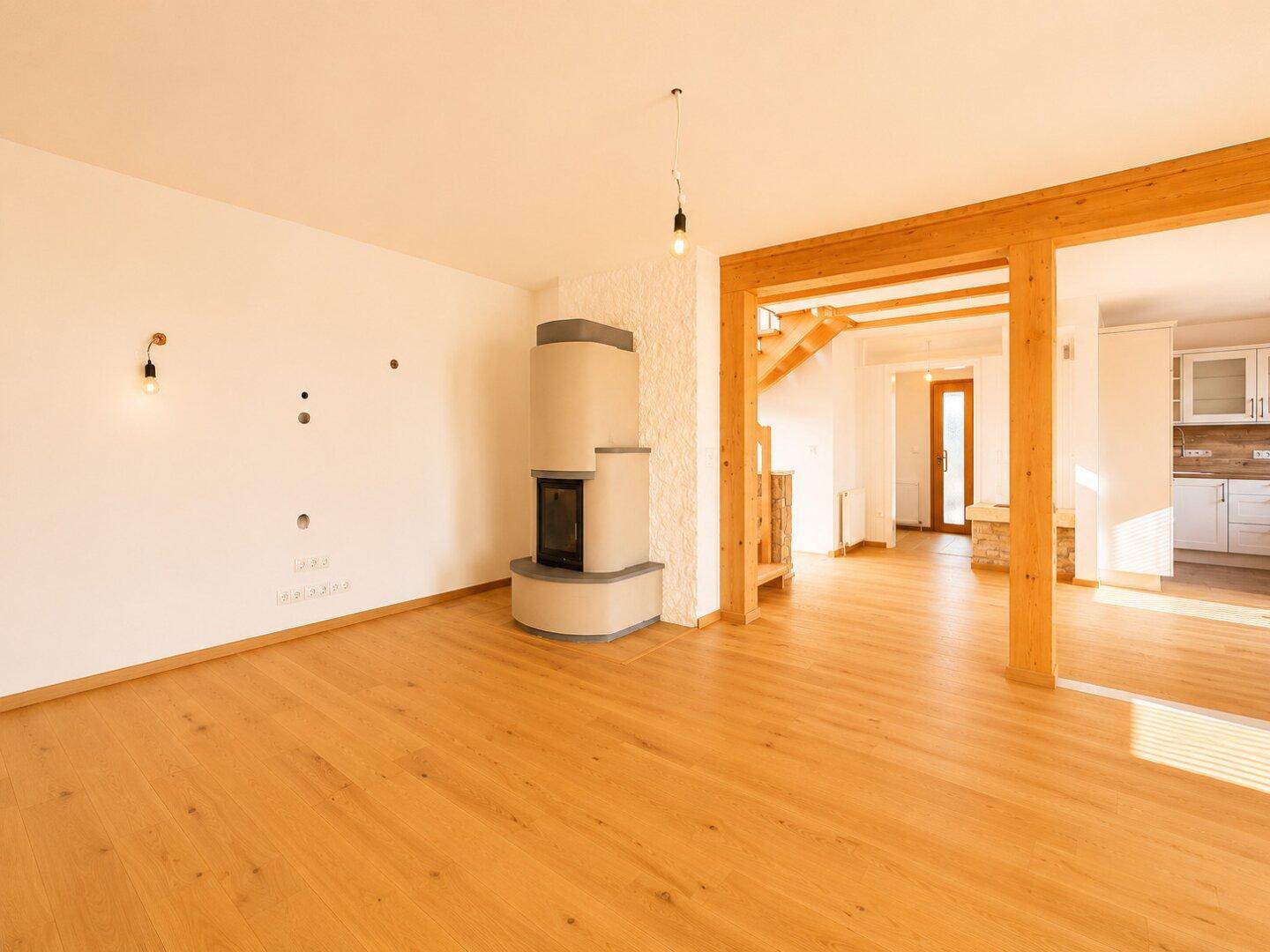 Gemütliches Wohnzimmer mit modernem Kaminofen, Holzbalken und hellem Parkettboden.