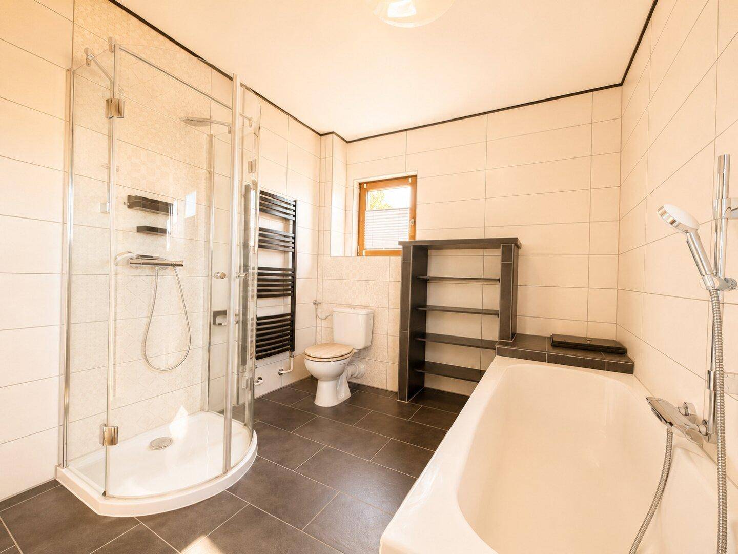 Modernes Badezimmer mit Dusche, Badewanne, WC und beheiztem Handtuchhalter.
