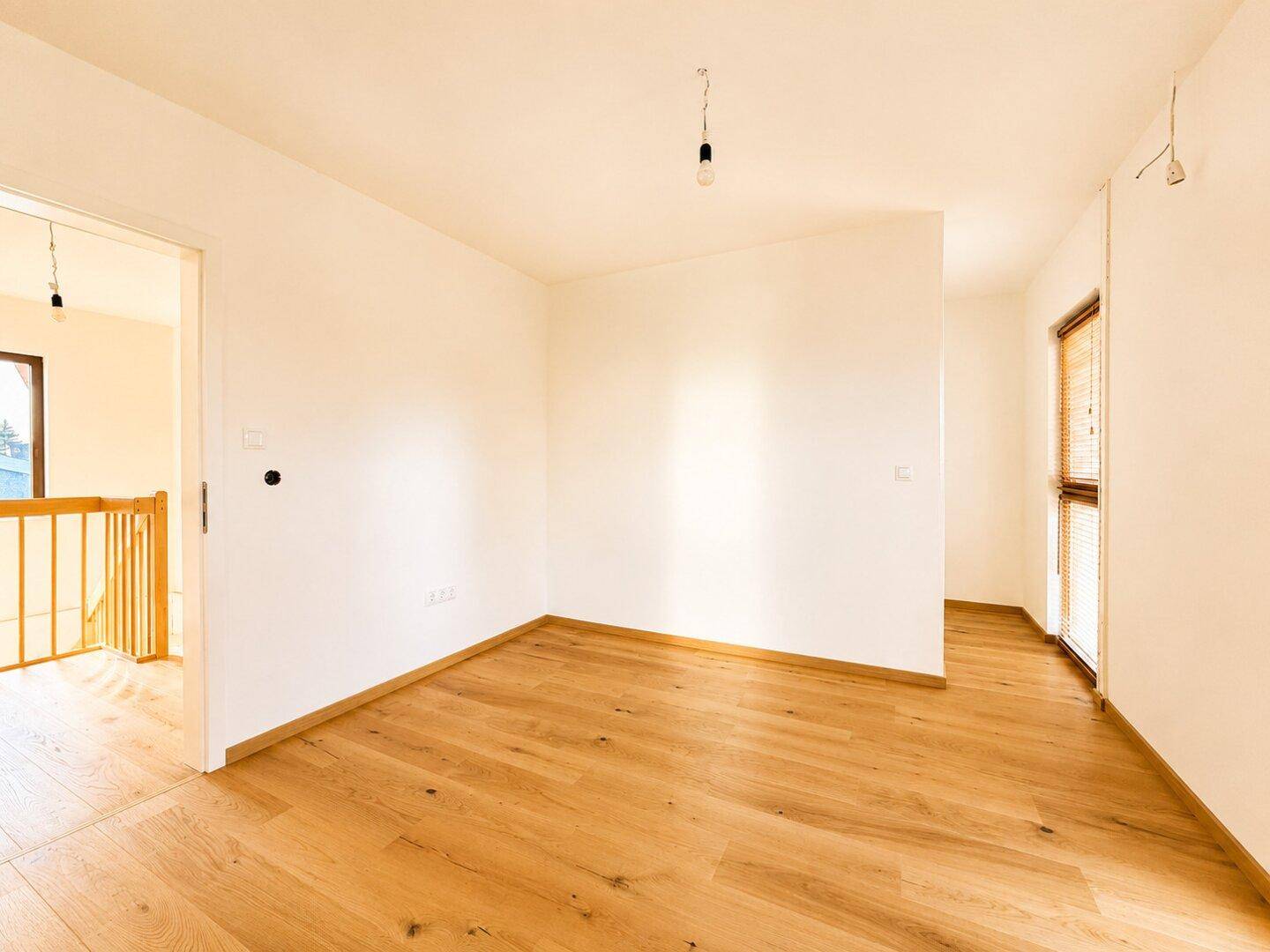 Helles, leeres Zimmer mit Parkettboden und Fenster, bereit zur individuellen Gestaltung.