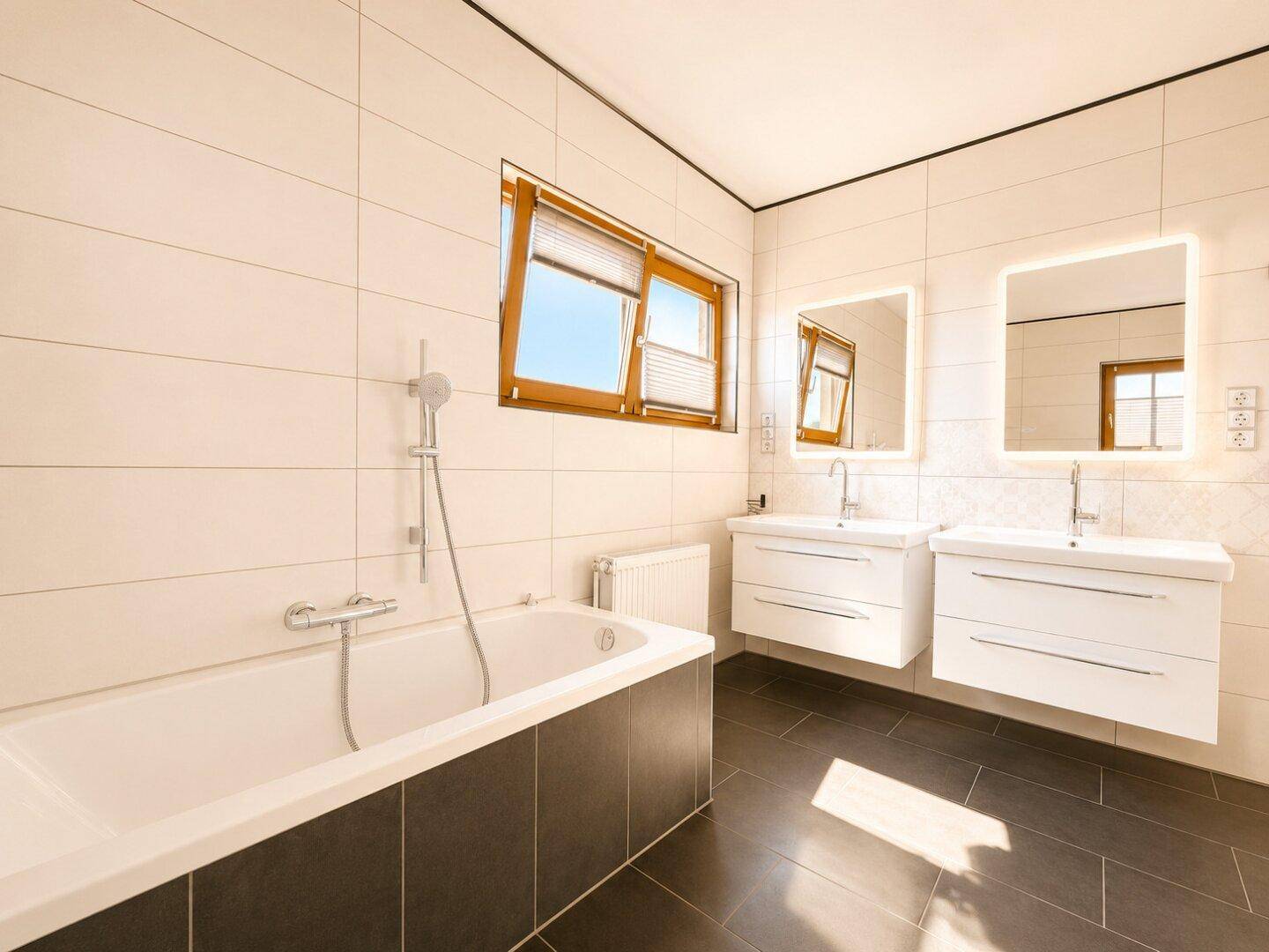 Geräumiges Badezimmer mit Doppelwaschbecken, Badewanne und großem Fenster.