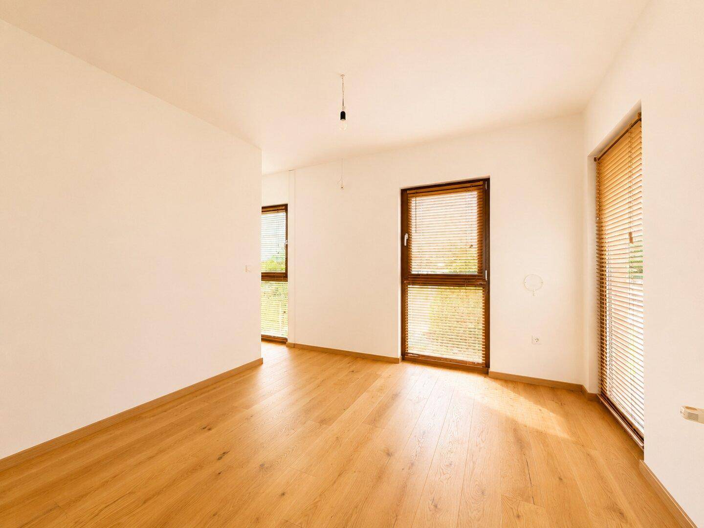 Geräumiges Zimmer mit Parkettboden und zwei Fenstern, ideal als Schlaf- oder Arbeitszimmer.