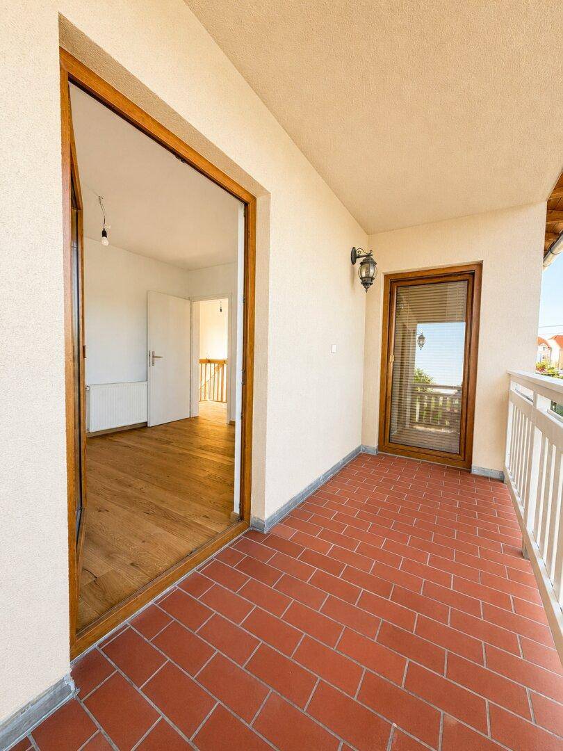 Geräumiger Balkon mit Terrakottafliesen und Zugang zu einem hellen Innenraum.