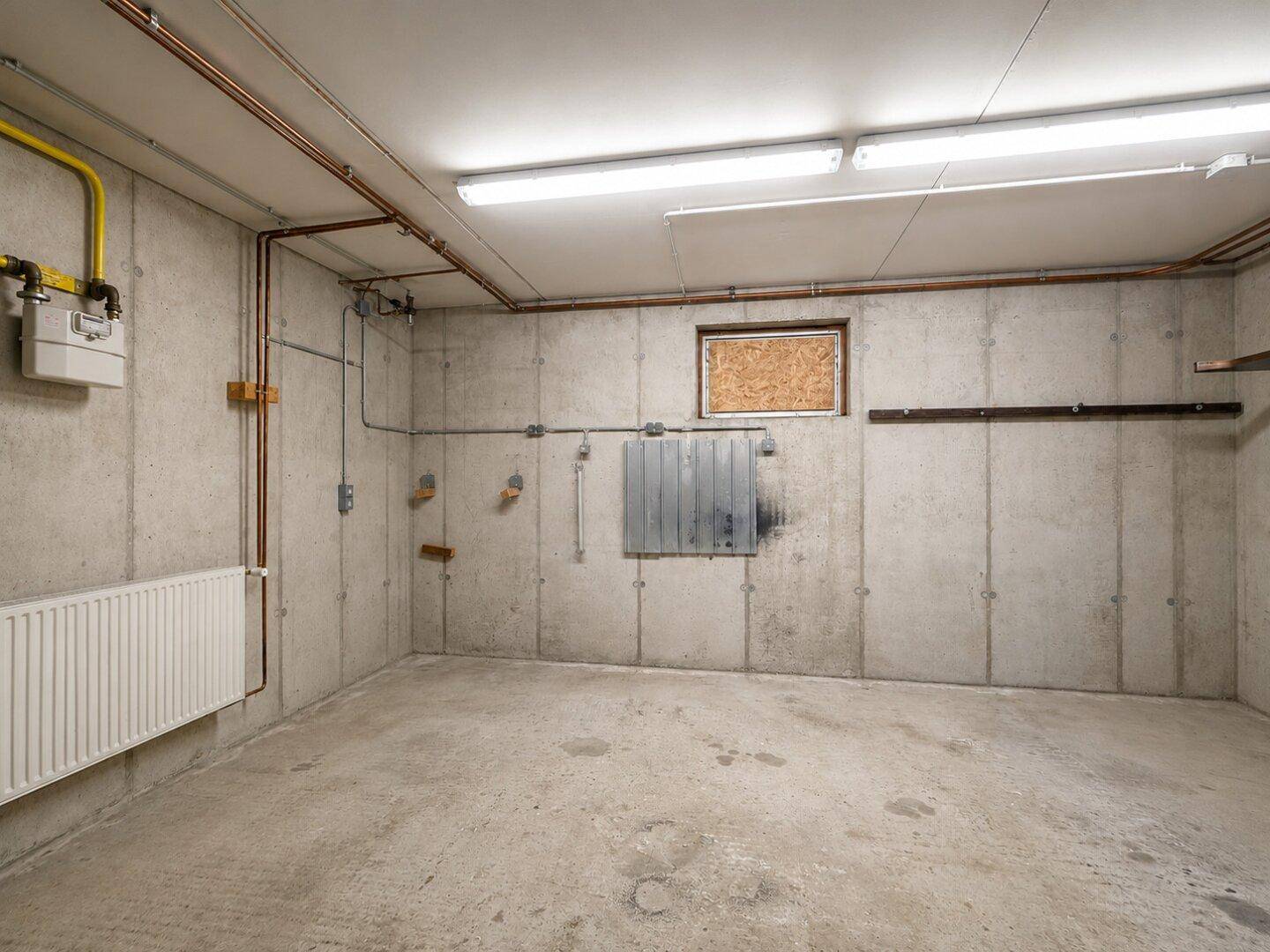 Geräumiger Kellerraum mit Betonwänden und -boden, ideal als Lager oder Werkstatt.