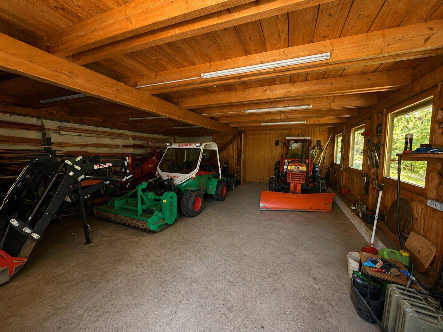 Geräumige Scheune mit Holzbalken, Fenstern und landwirtschaftlichen Maschinen.