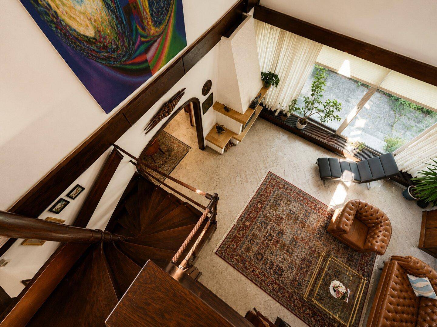 Geräumiges Wohnzimmer mit hoher Decke, Wendeltreppe und Kamin, von oben fotografiert.