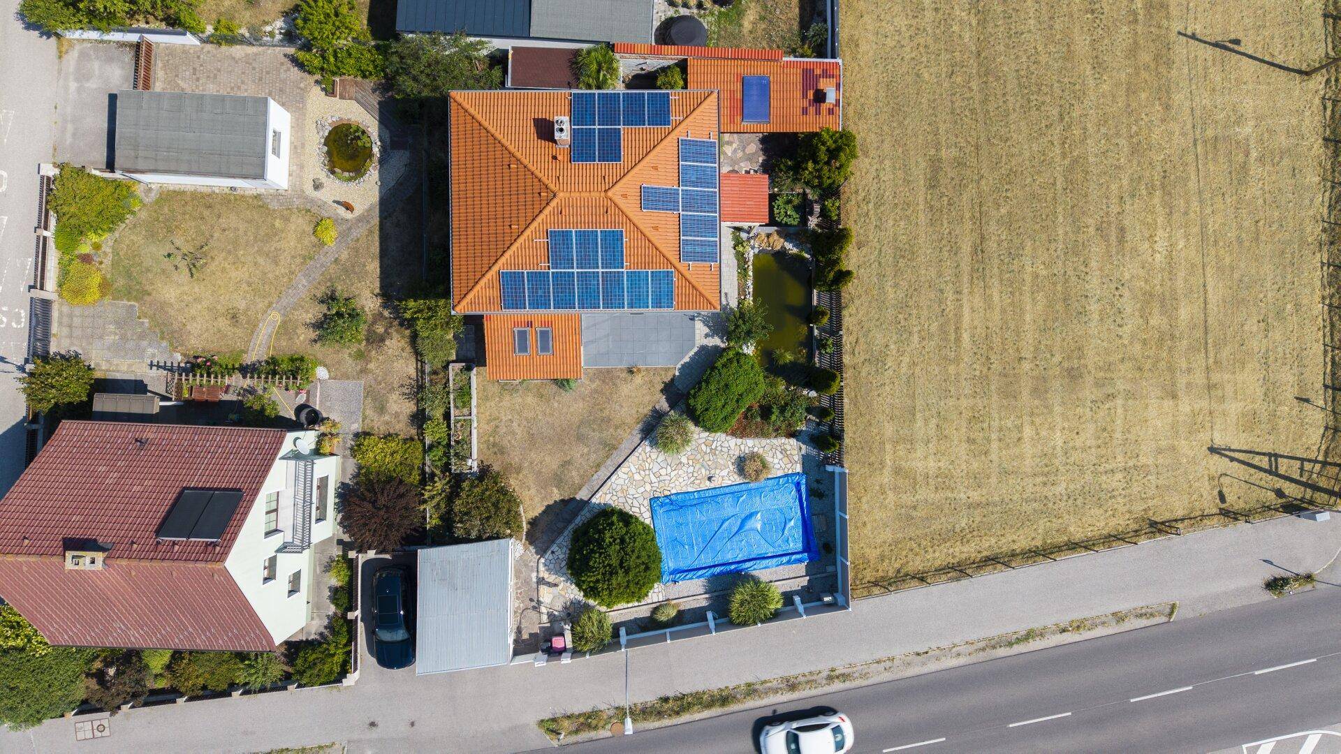 Luftaufnahme des Hauses mit Solaranlage auf dem Dach und großem Garten mit Pool.
