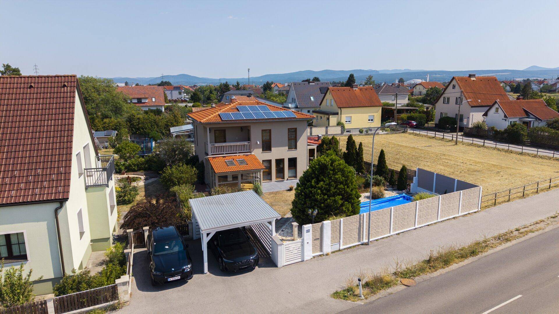 Weitläufige Ansicht des Hauses mit Solaranlage, Pool und Carport, umgeben von Natur.