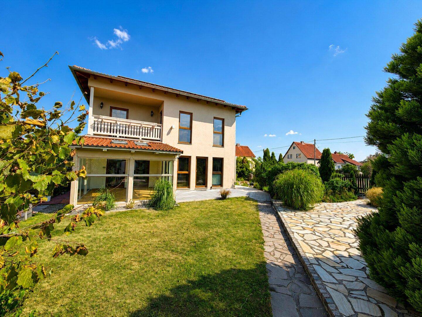 Gepflegter Gartenbereich mit Steinweg und Blick auf die moderne Hausfassade.
