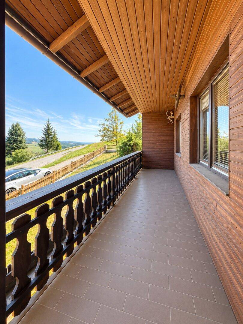 Überdachter Balkon mit Fliesenboden und traditionellem Holzgeländer, bietet einen weiten Ausblick.