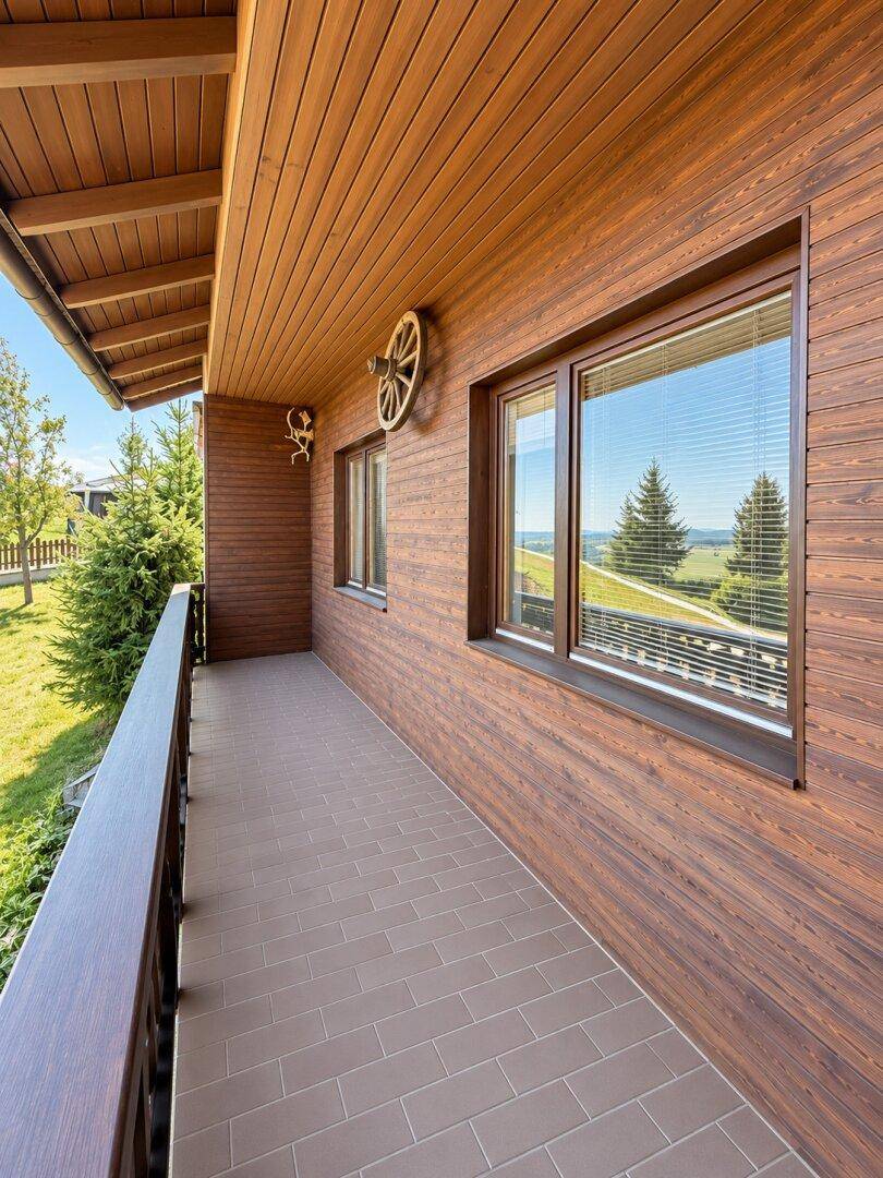 Langer Balkon mit Holzwänden und Fliesenboden, ideal zum Entspannen mit schöner Aussicht.