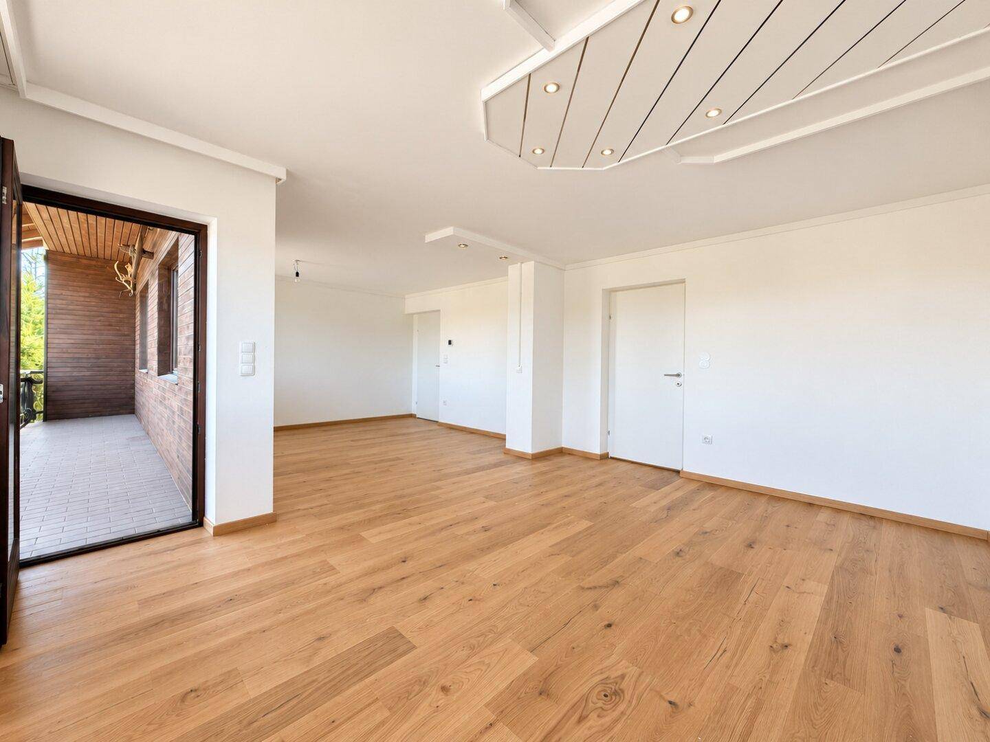 Geräumiger Wohnbereich mit Holzboden und Zugang zum Balkon, bietet viel Gestaltungspotenzial.