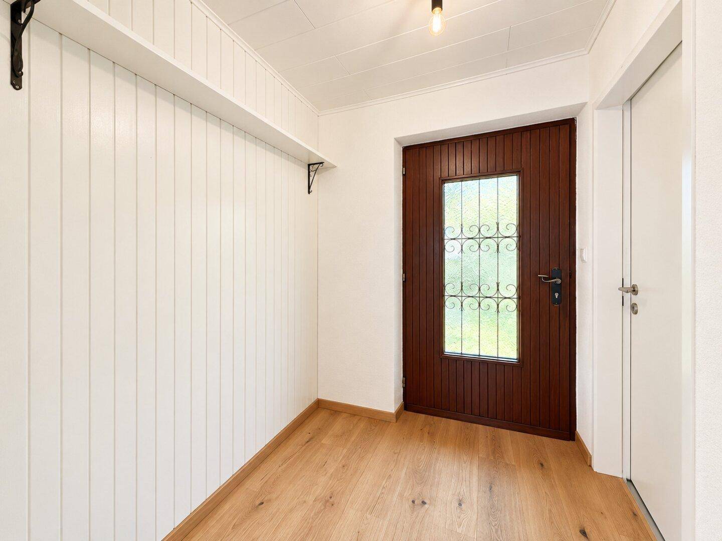 Gemütlicher Flur mit weißer Holzvertäfelung und Holzboden, ideal für eine Garderobe.