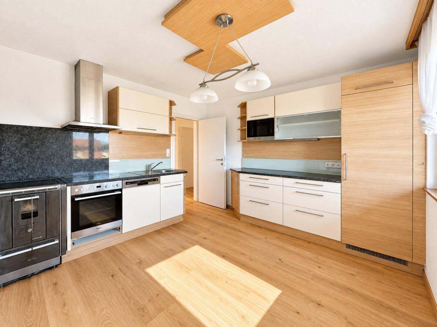 Moderne Einbauküche mit Holz- und weißen Fronten, Granitarbeitsplatte und integrierten Geräten.
