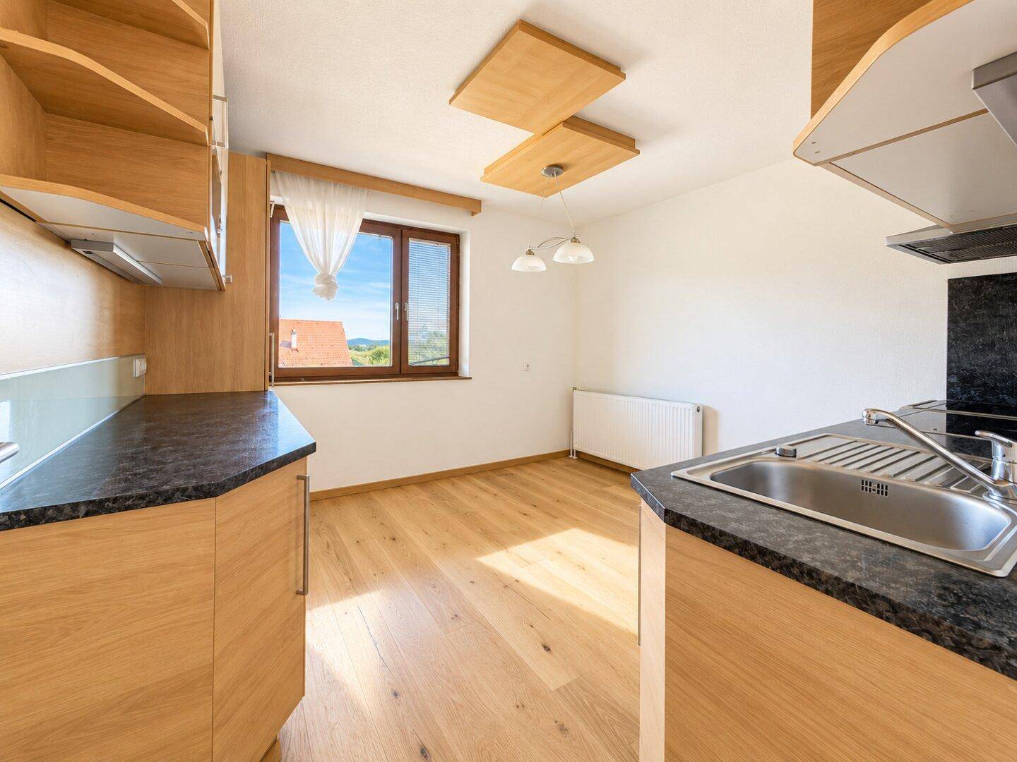 Heller Essbereich in der Küche mit Holzboden und Fenster, das einen schönen Ausblick bietet.