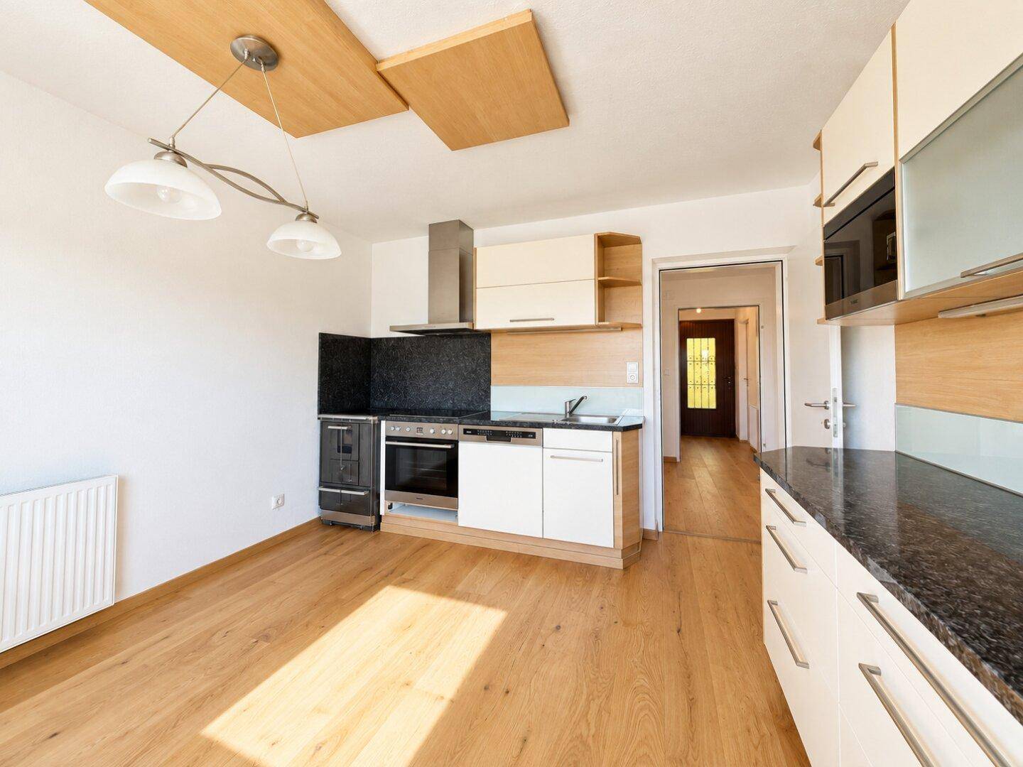 Gut ausgestattete Küche mit Holz- und weißen Schränken, Granitarbeitsplatte und Essbereich.