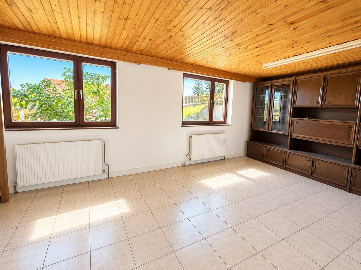 Großer Raum mit Fliesenboden, Holzdecke und Einbauschrank, bietet vielfältige Nutzungsmöglichkeiten.