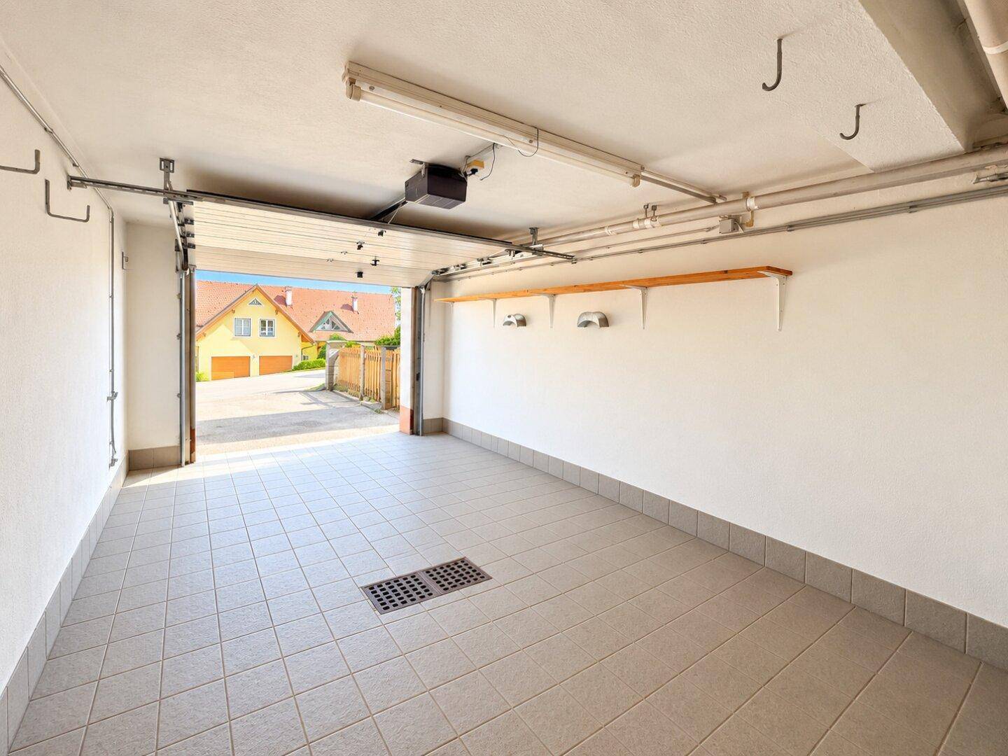 Helle Garage mit Fliesenboden und Blick nach draußen, ideal als Abstell- oder Werkstattraum.