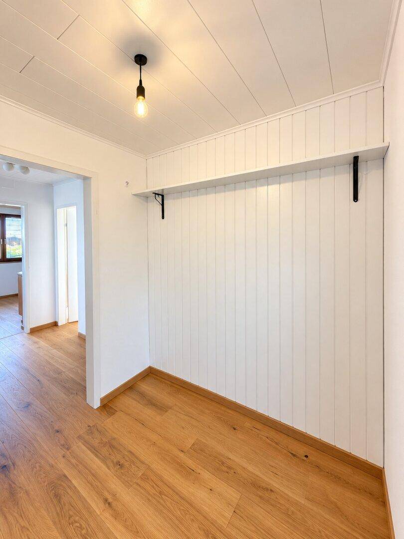 Freundlicher Flur mit weißer Wandvertäfelung und Holzboden, bietet Platz für individuelle Gestaltung.