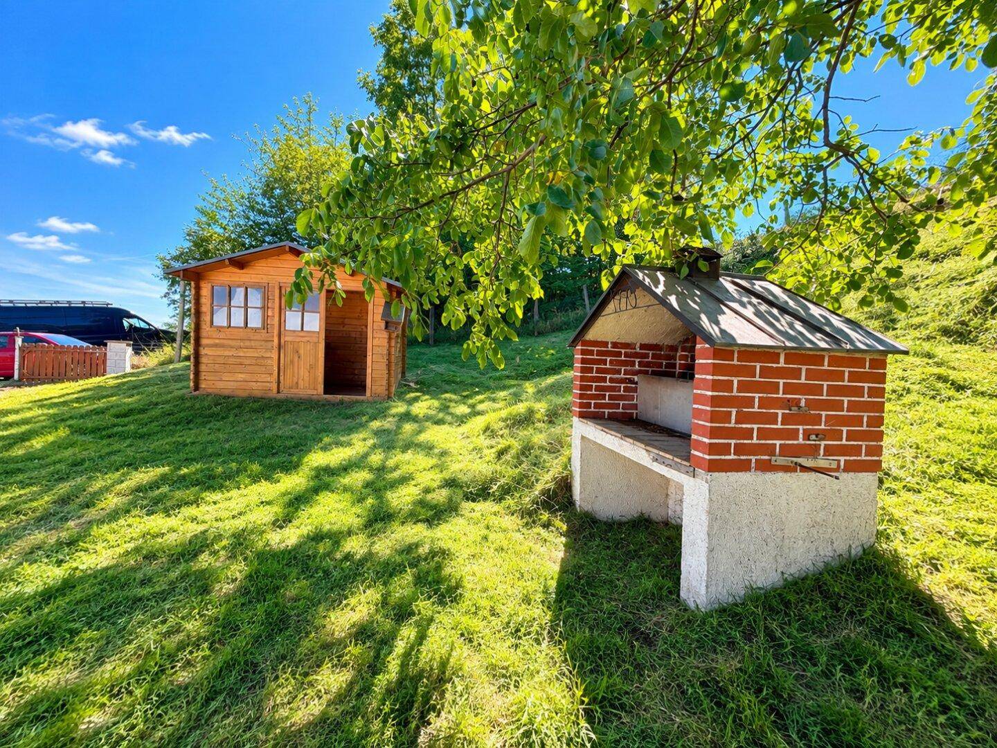 Weitläufiger Garten mit einem praktischen Holzschuppen und einem gemauerten Grill für Outdoor-Aktivitäten.