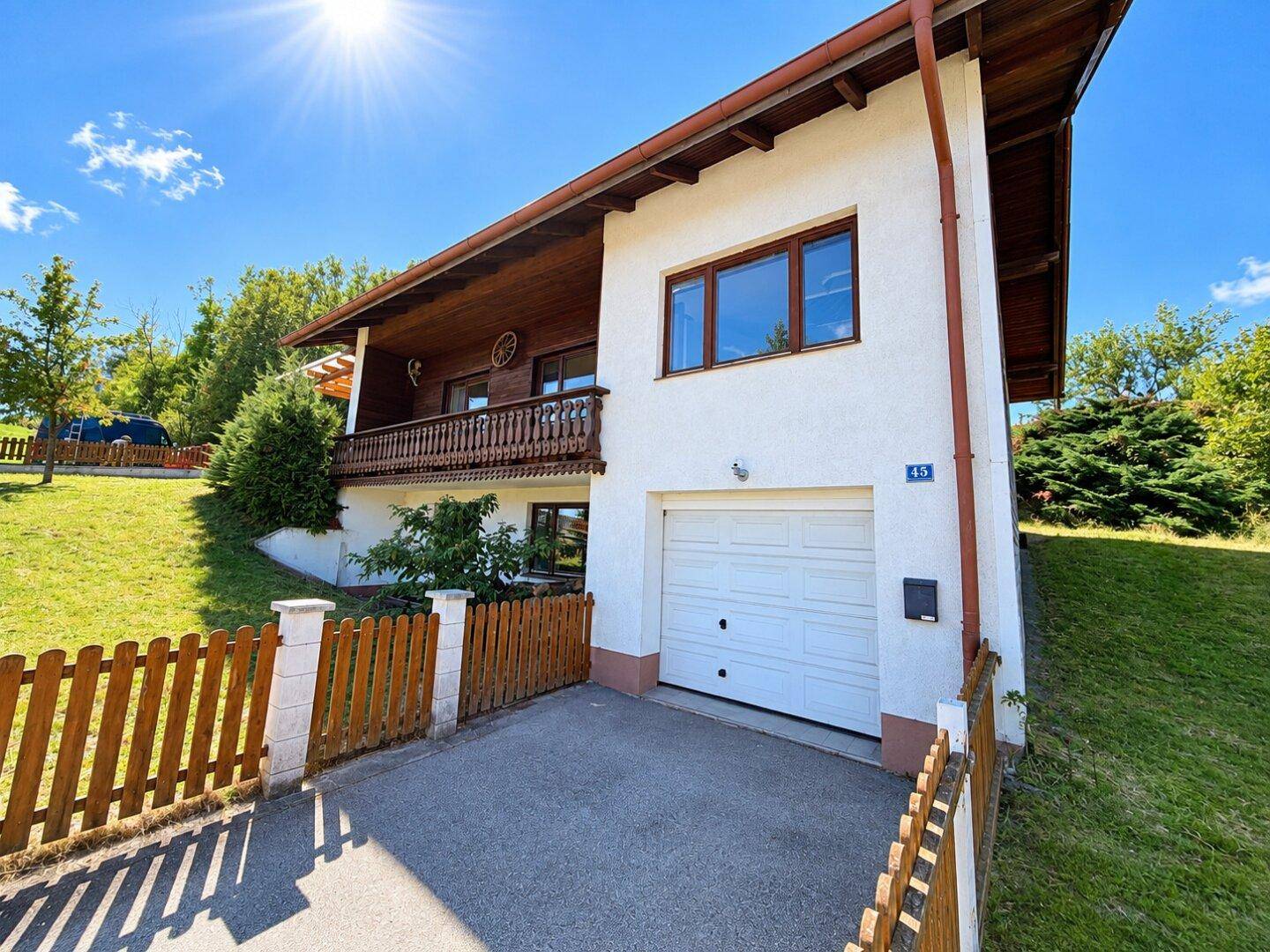 Charmantes Haus mit integrierter Garage und sonnigem Vorgarten in ländlicher Umgebung.