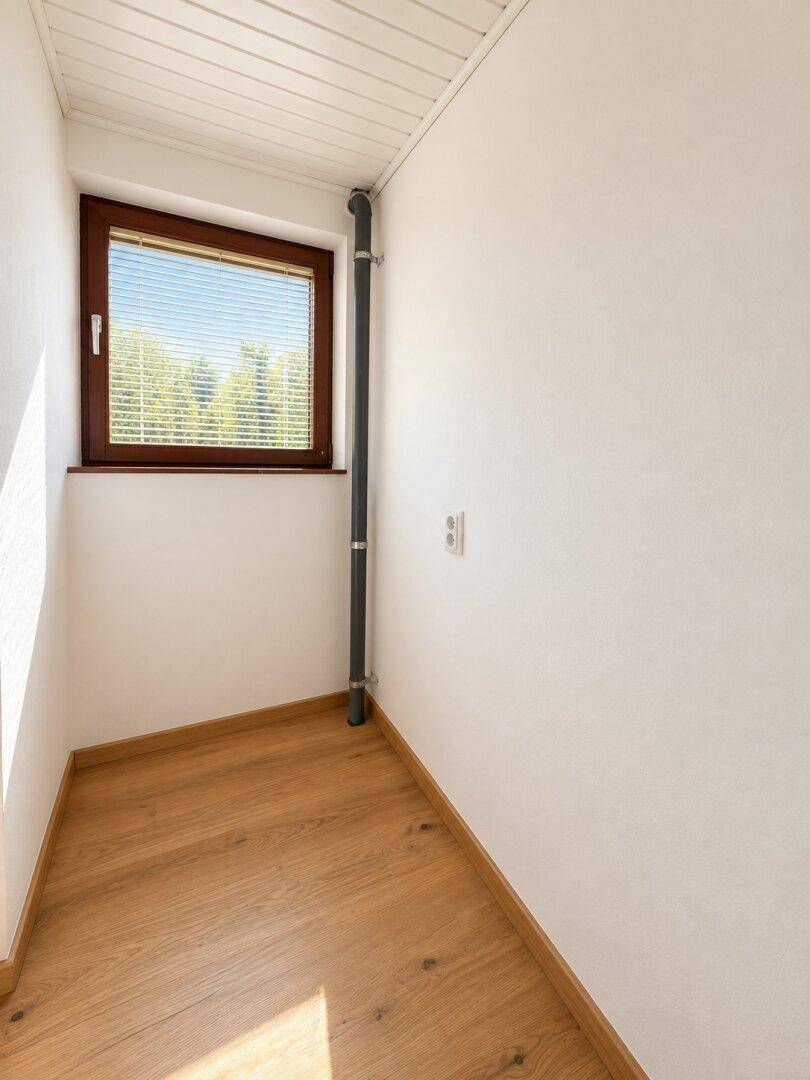 Kleiner Abstellraum mit Holzboden und Fenster, ideal für zusätzlichen Stauraum.