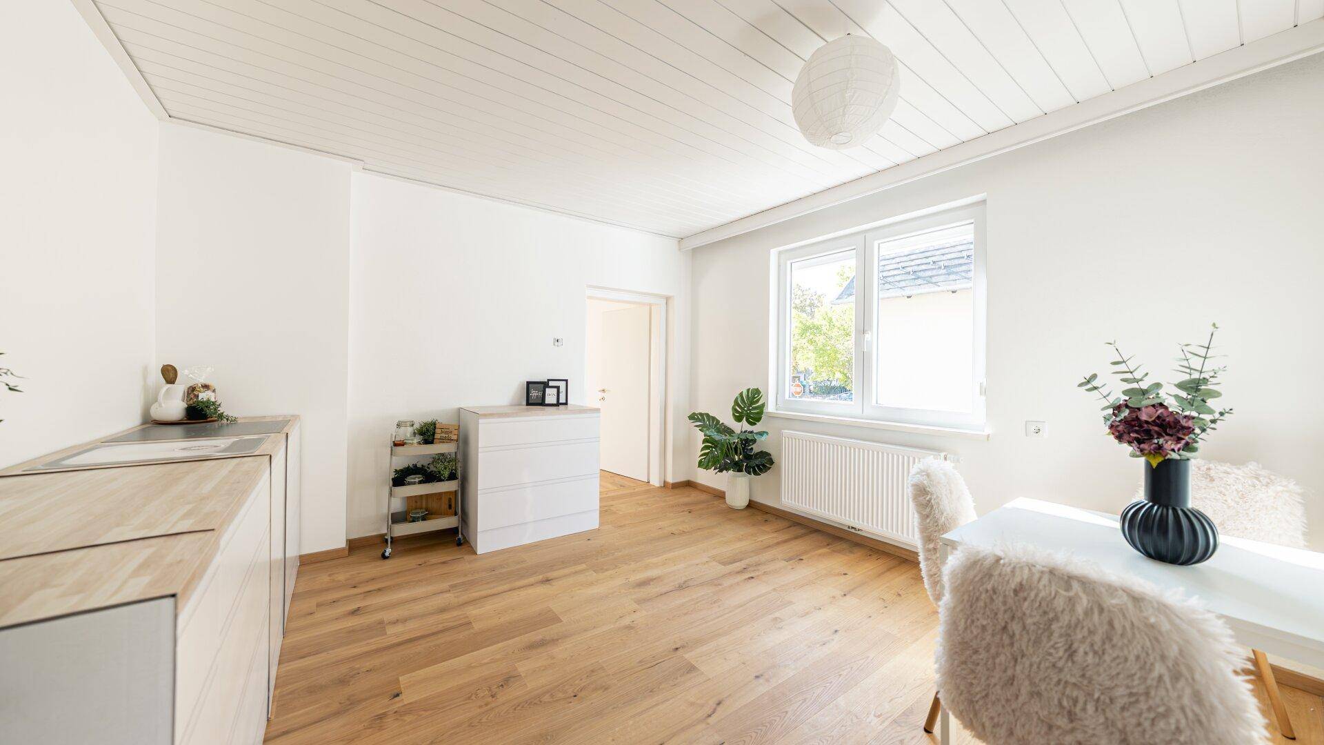 Heller Essbereich mit Holzboden, weißer Deckenverkleidung und modernem Esstisch.
