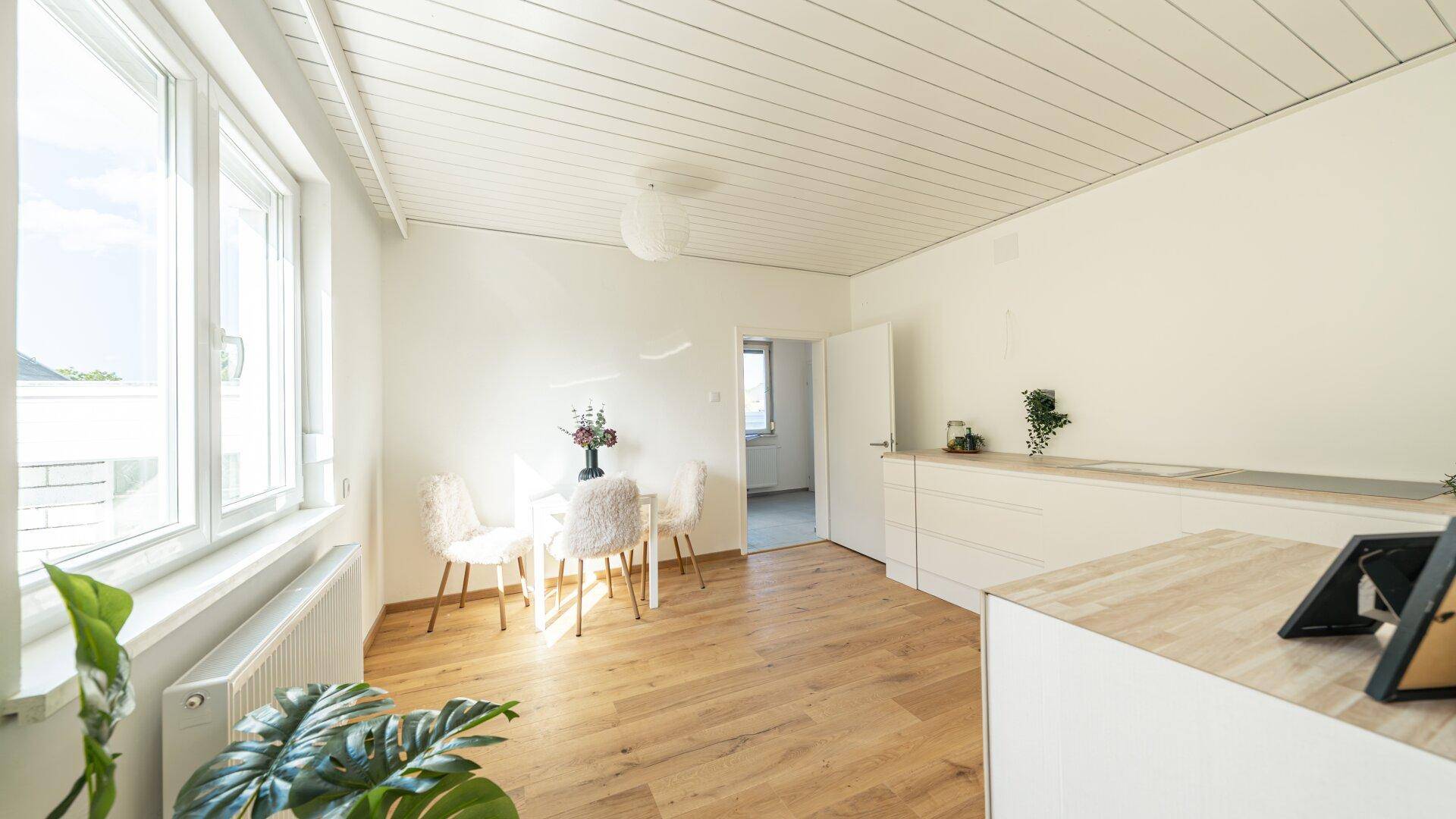 Lichtdurchfluteter Essbereich mit Holzboden, weißer Deckenverkleidung und modernem Esstisch.