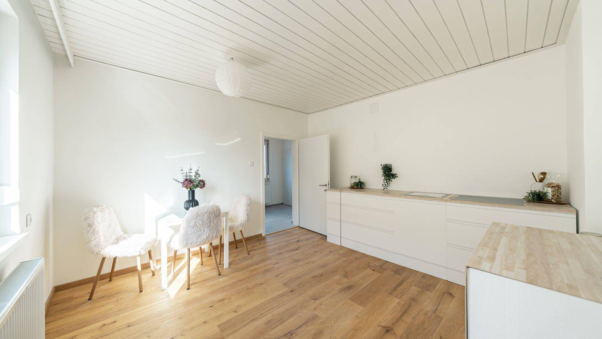 Heller Essbereich mit Holzboden, weißer Deckenverkleidung und modernem Esstisch.