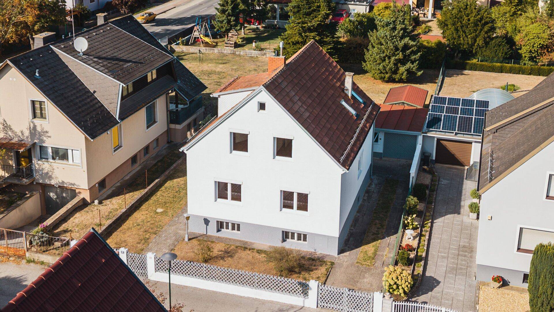 Vogelperspektive des Einfamilienhauses mit gepflegtem Vorgarten und umgebenden Wohnhäusern in ländlicher Umgebung.