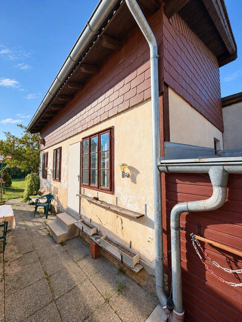 Seitenansicht des Hauses mit Terrasse, Außentür und Blick auf den Gartenbereich.