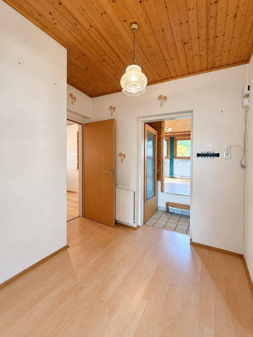 Flur mit Holzdecke, Laminatboden und Zugang zu mehreren Zimmern.