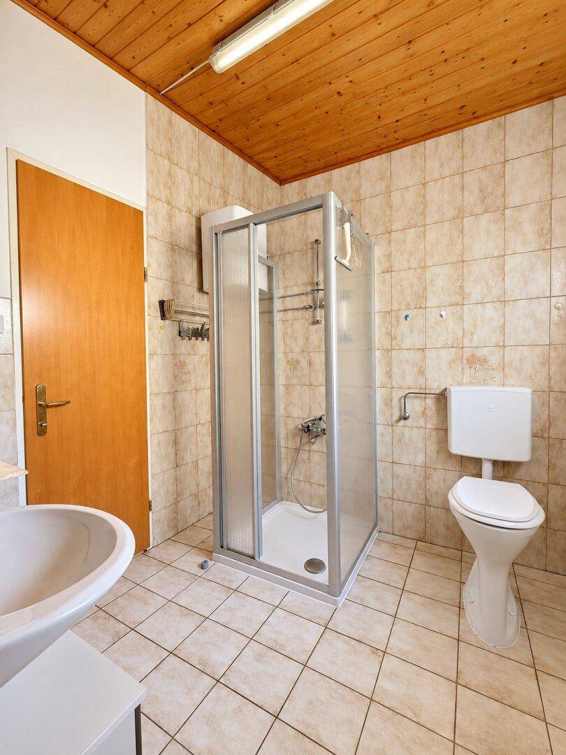 Badezimmer mit gefliesten Wänden und Boden, Duschkabine und WC.